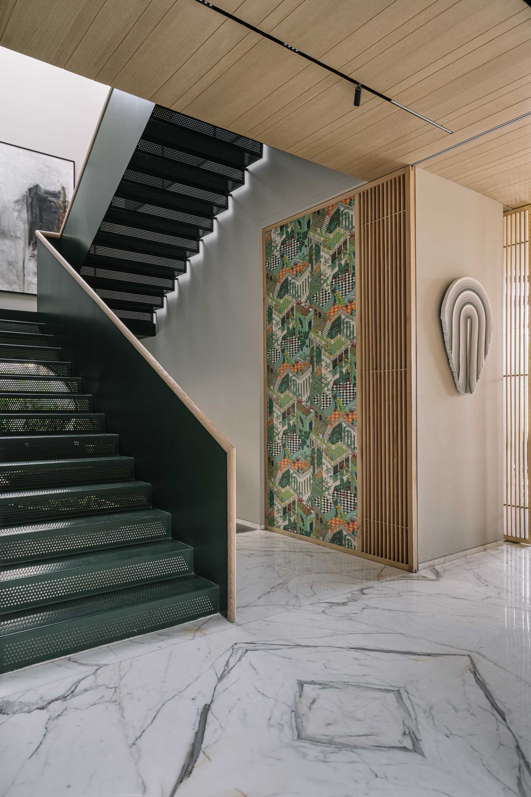 Metal stairs with a wood handrail are lit by a skylight above, while below, there's a seating area tucked in near a round window.