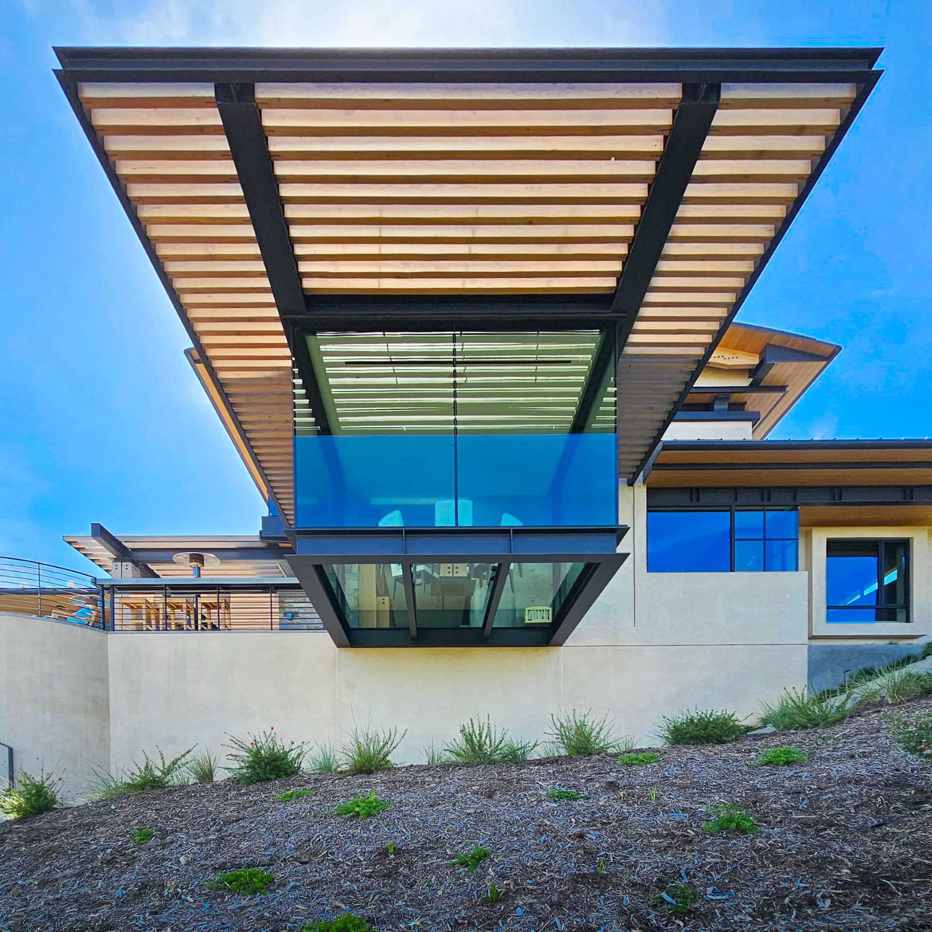 A cantilevered dining area, with glass walls and floor supported by steel beams.