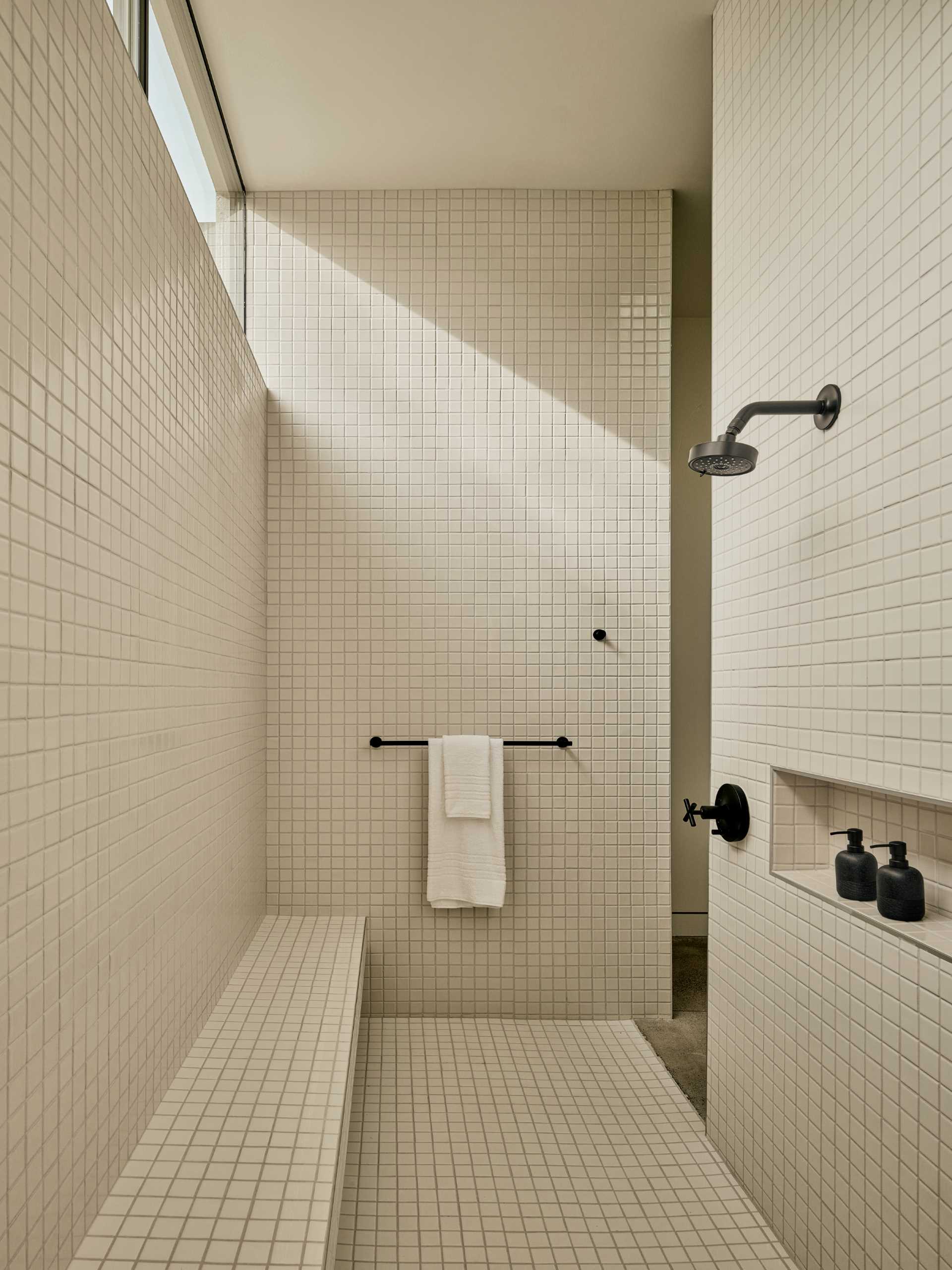 Square tiles cover the walls, floors, and bench in this shower that also includes a shelving nice.
