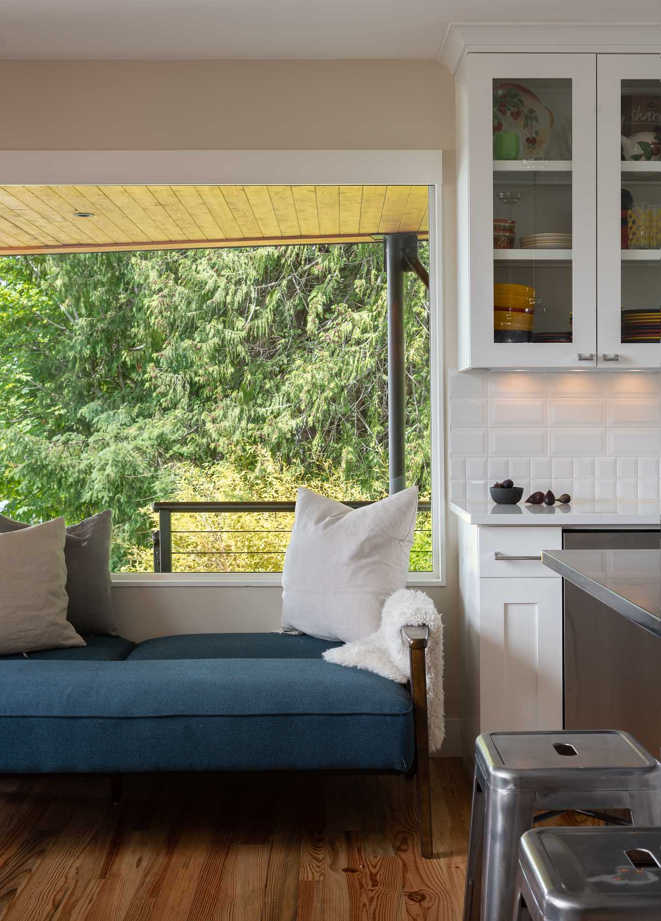 A contemporary living room and kitchen with reclaimed wood flooring and picture windows.