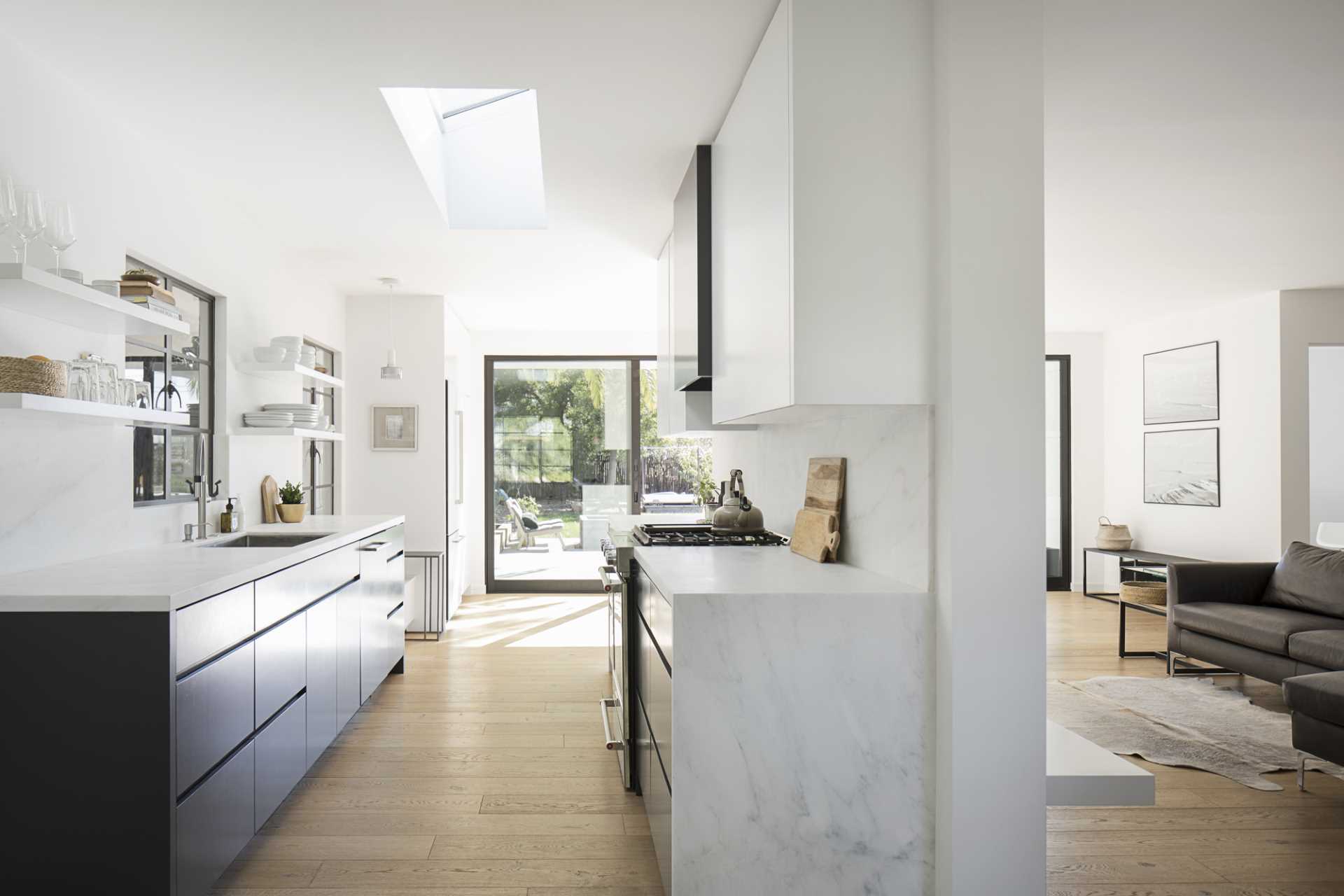 A modern black and white kitchen with wood flooring.