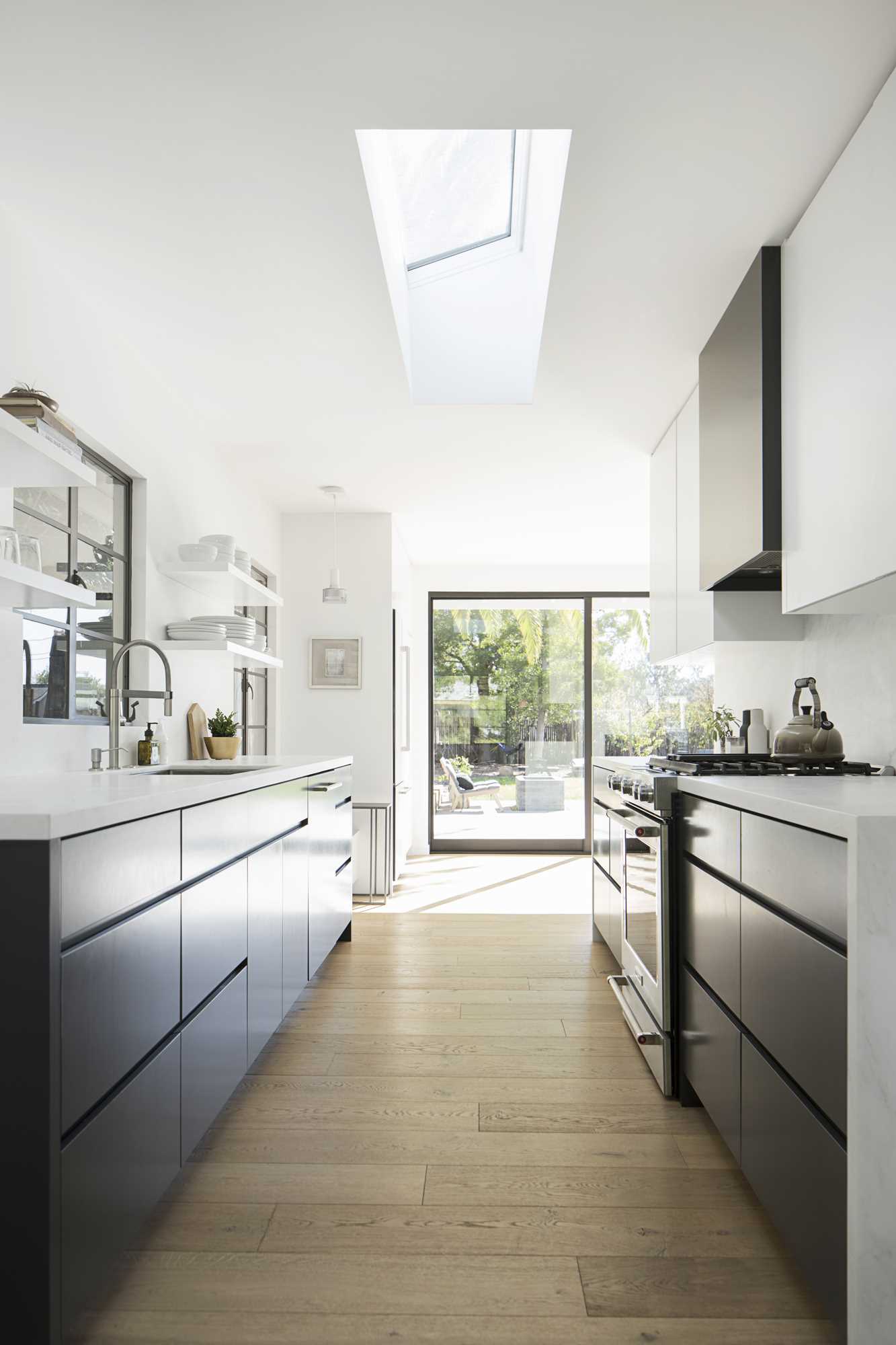 A modern black and white kitchen with wood flooring.