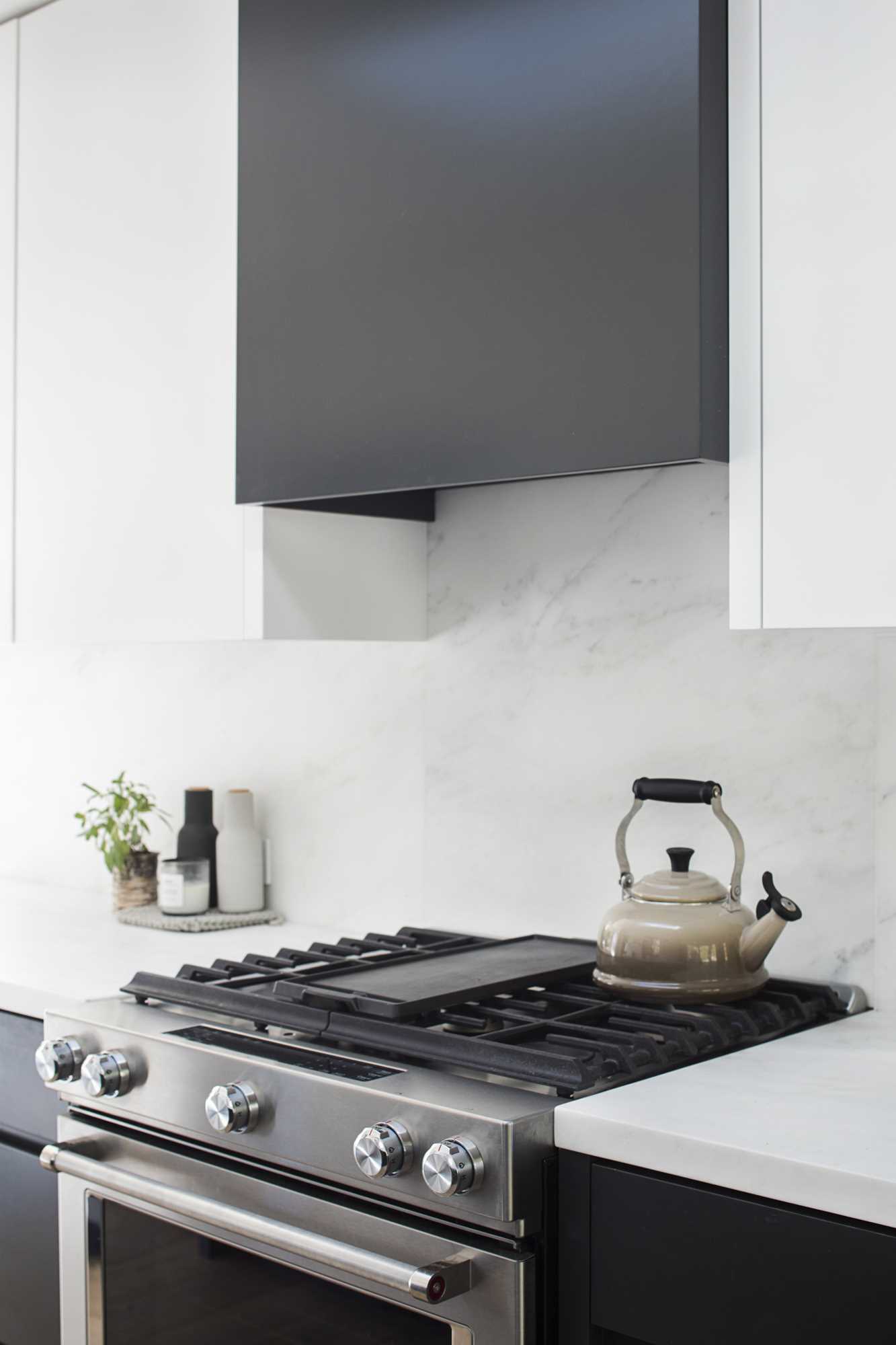 A modern black and white kitchen with wood flooring.