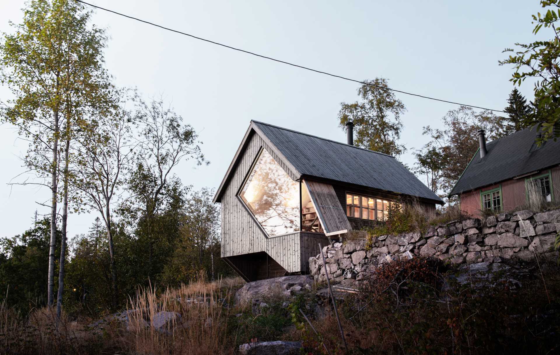 A contemporary cabin designed to include a uniquely shaped window that perfectly frames the sunset.