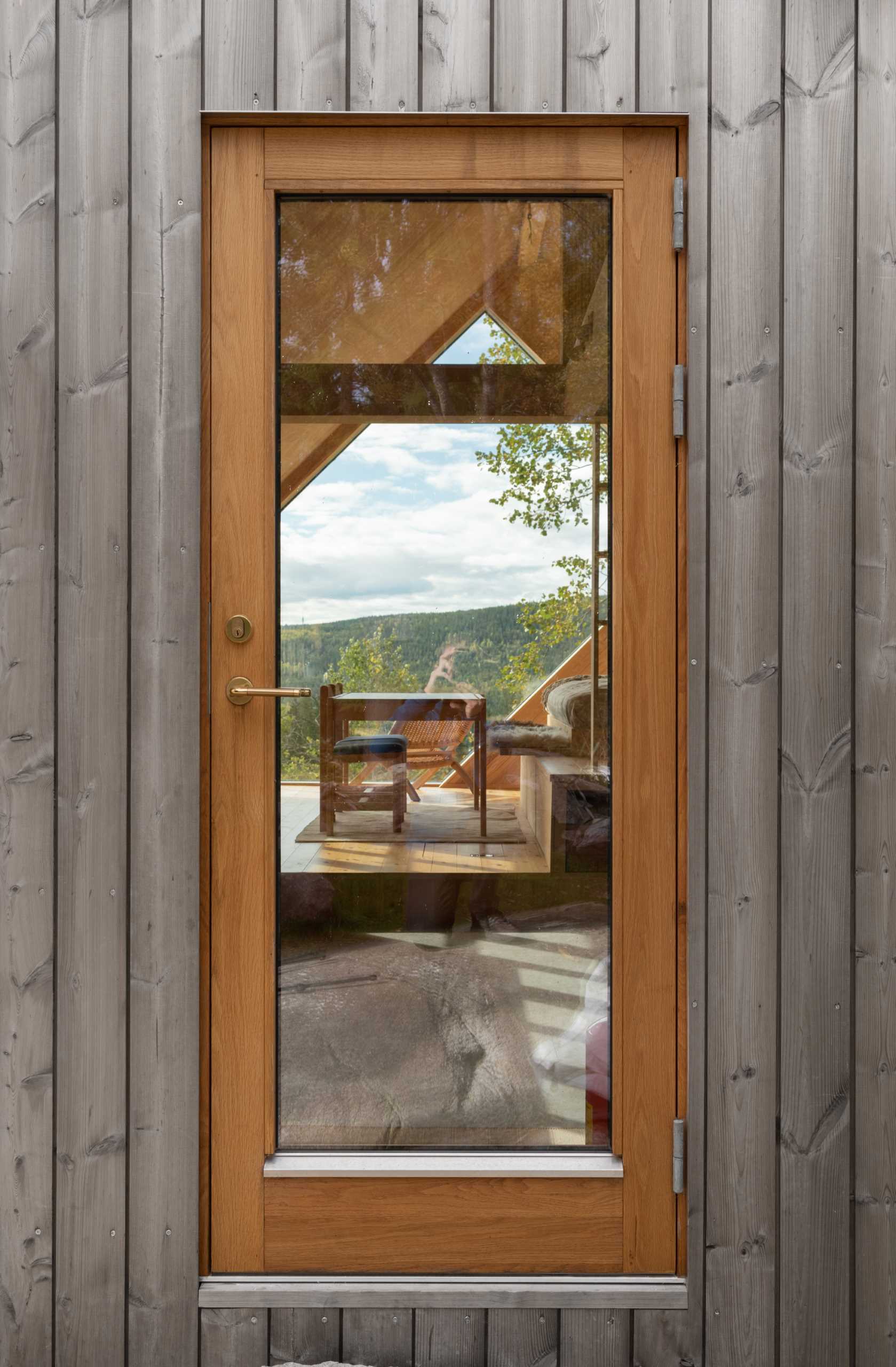 The wood-framed gl، door of a contemporary cabin.