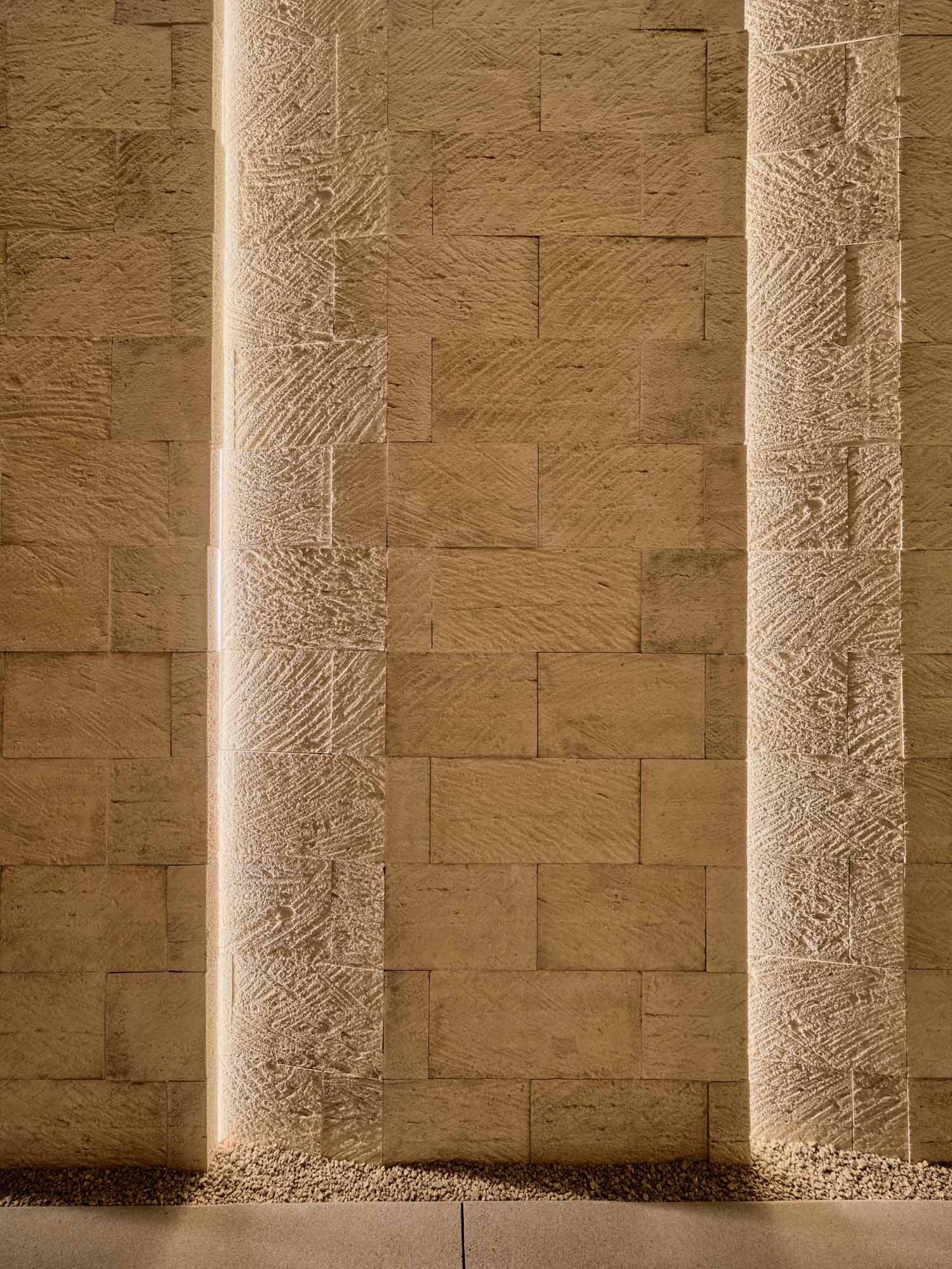 Lighting has been include between stone walls at the entryway of this modern desert home.
