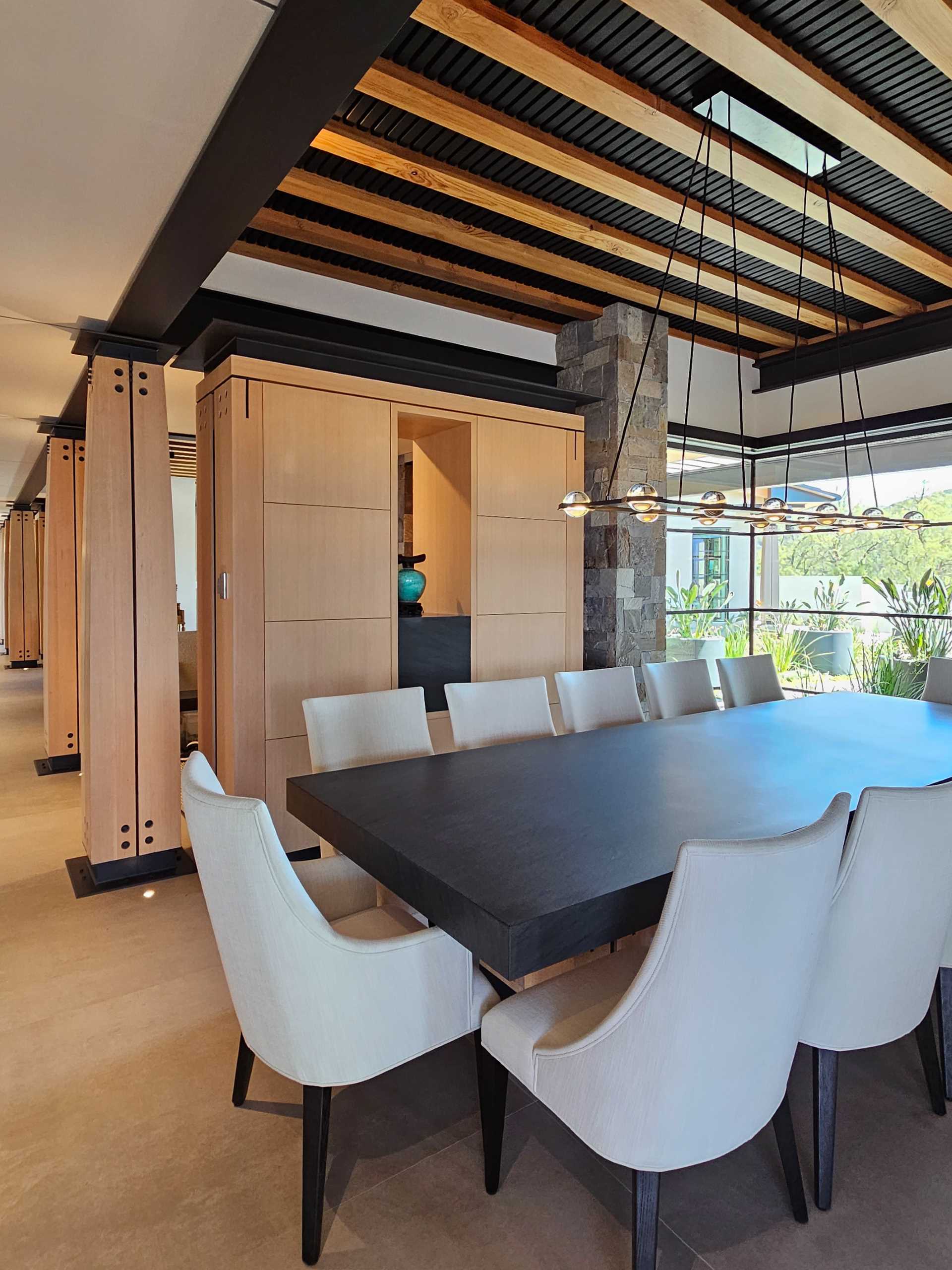 The dining room features a large table with a wood base that matches the nearby columns.