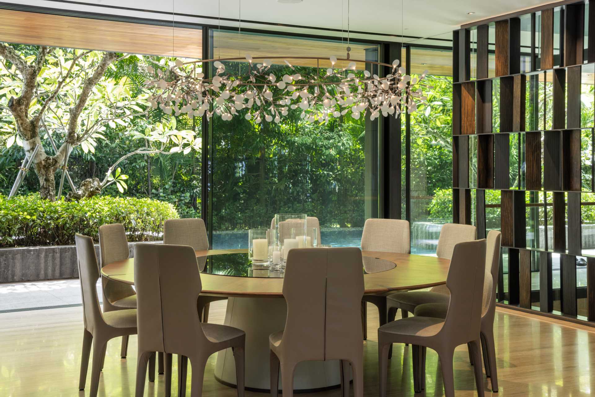 A modern dining room has glass walls that open to the outdoors.