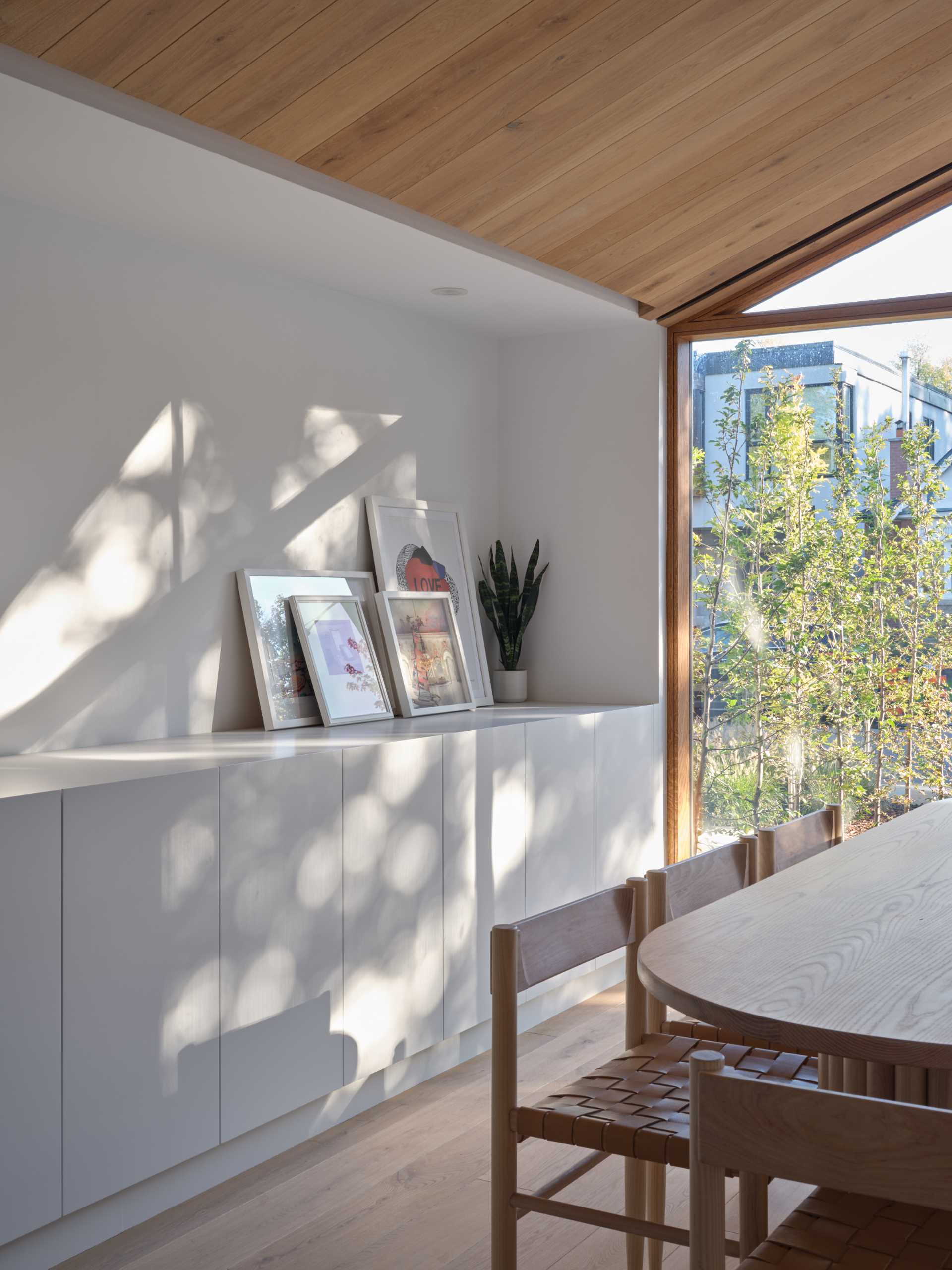 The kitchen cabinets transition into a built-in sideboard in the dining room that has views of the street outside.