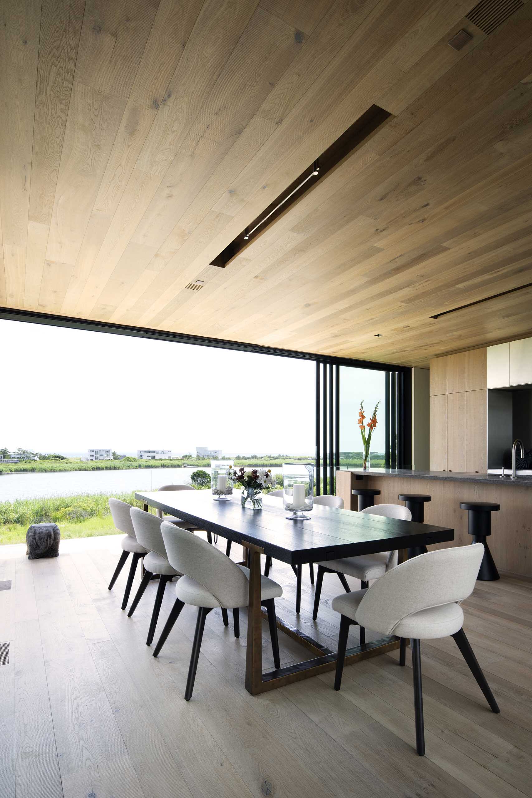The dining area and kitchen share the same space in this modern home, while the wood ceiling features recessed lighting.