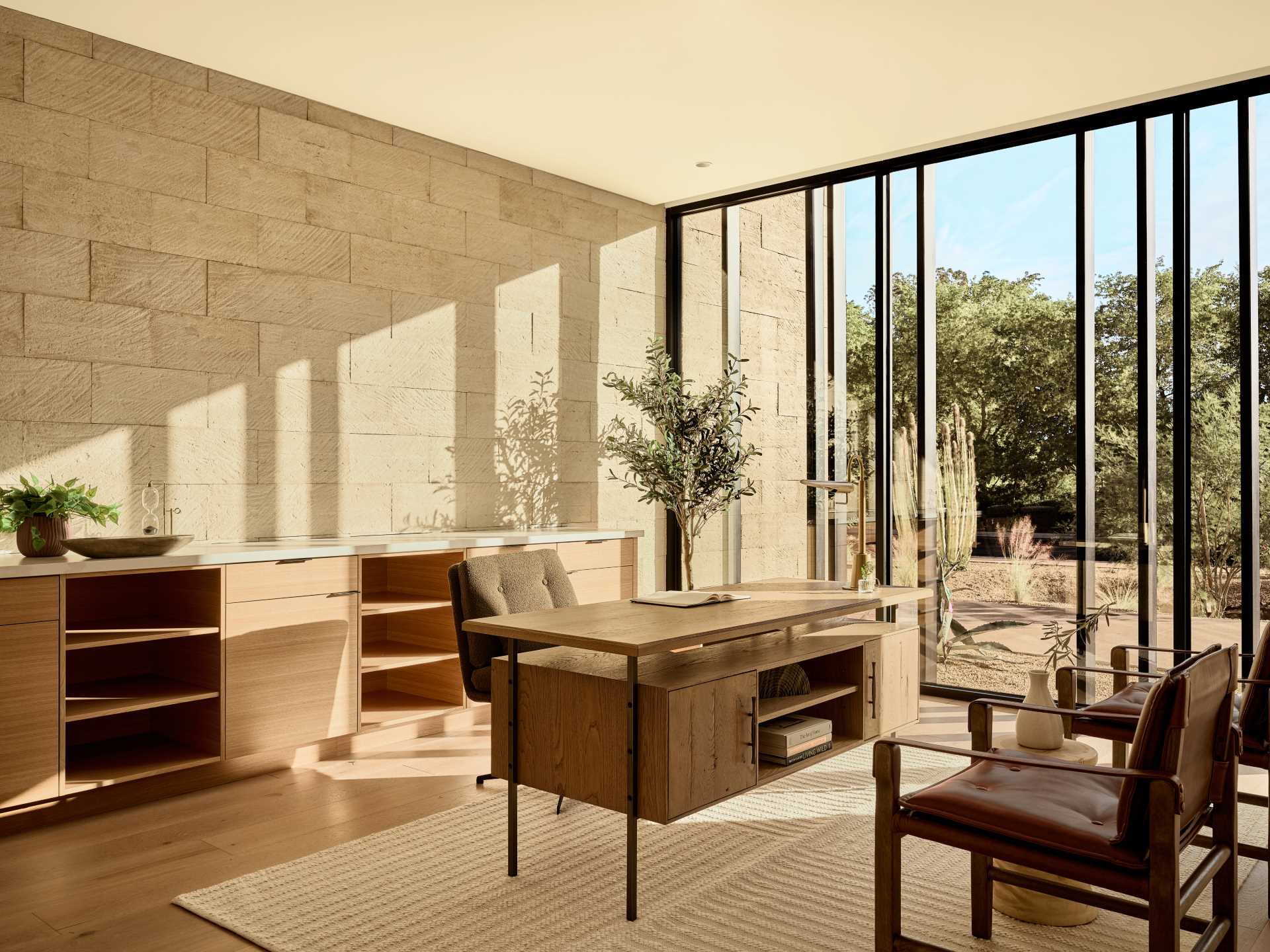 In this home office, floor-to-ceiling windows flood the room with natural light and provide a view of the desert landscape outside.