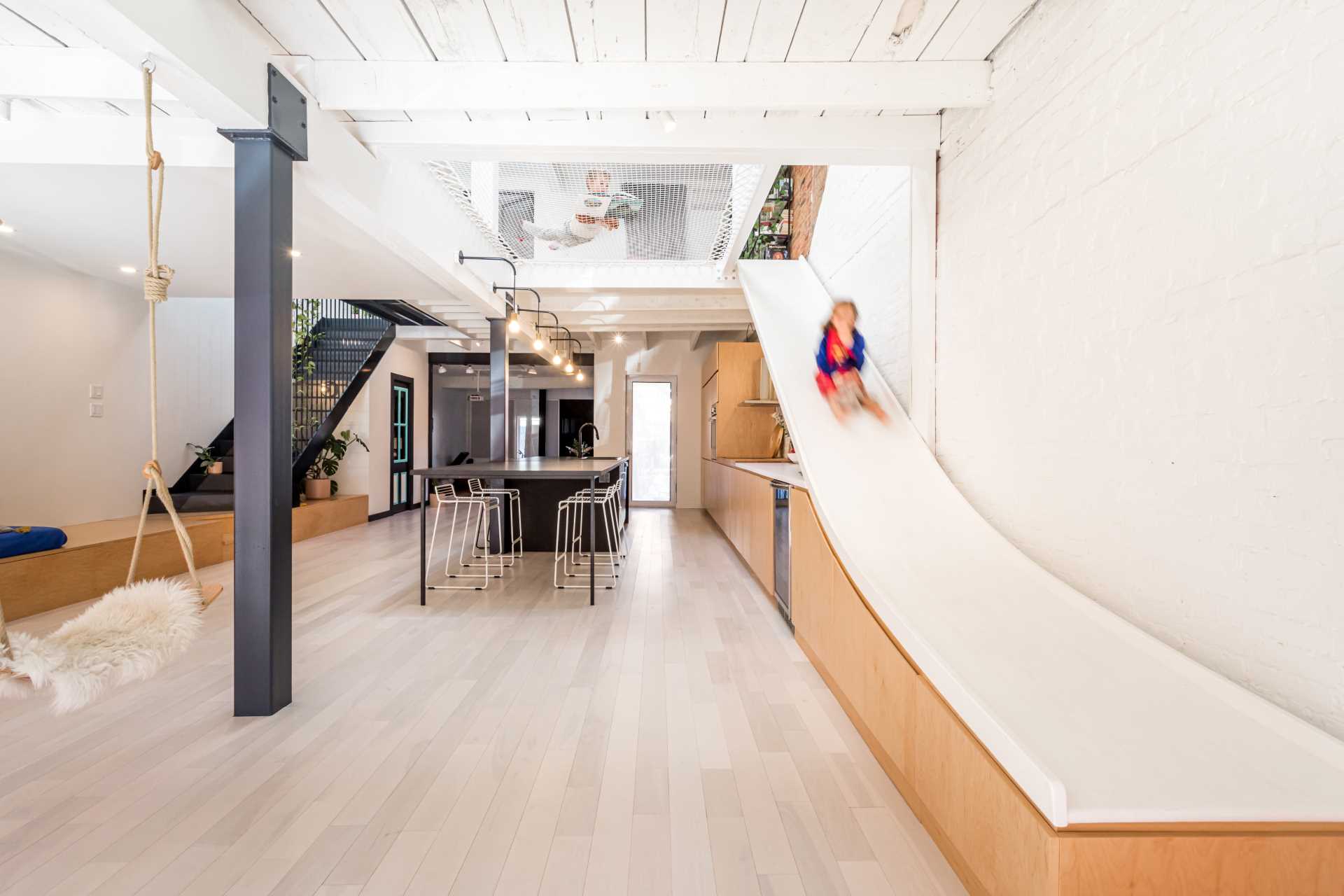 Indee Design has transformed a duplex into a single-family home, and included in the interior, is a slide that travels between floors.