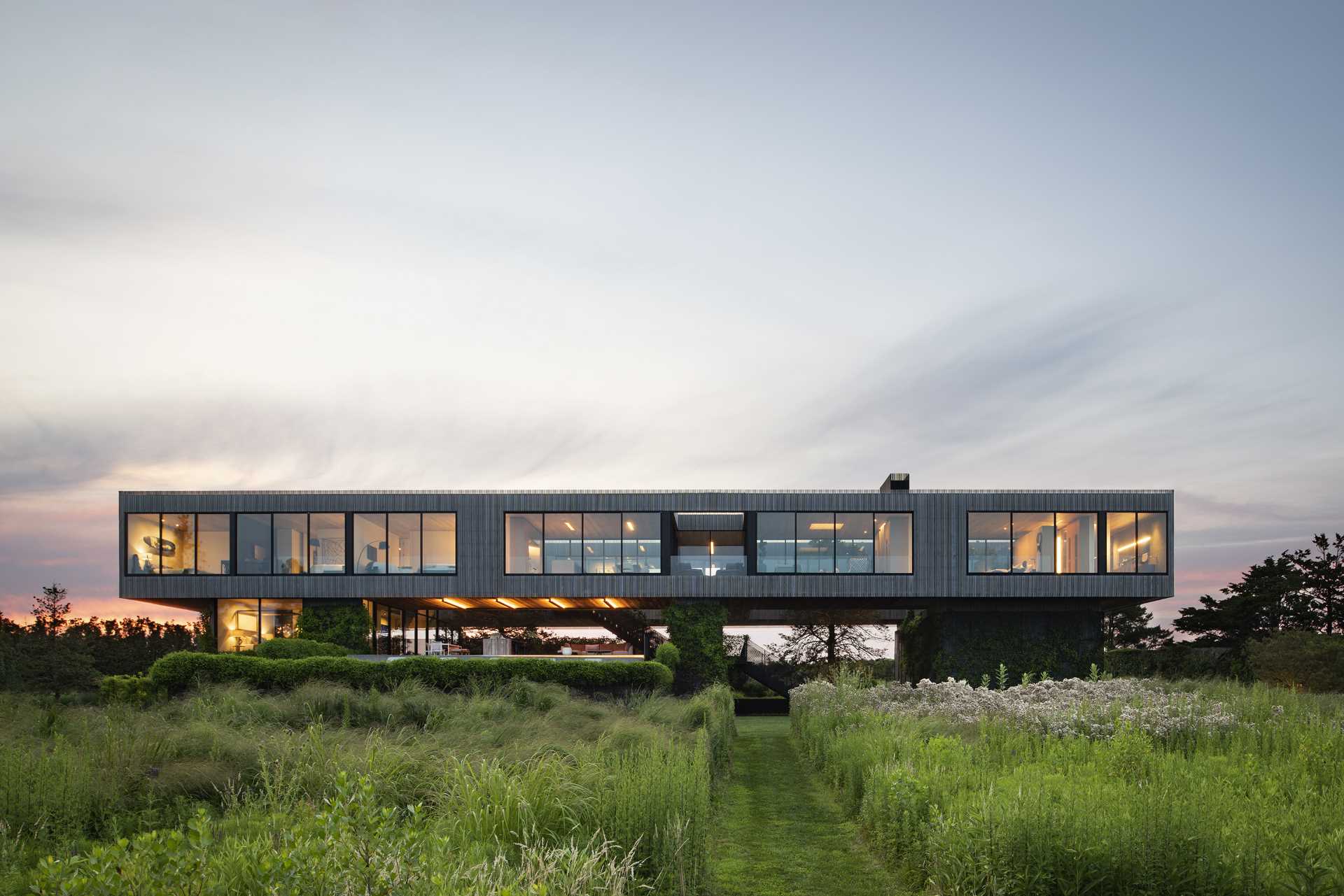 This elevated two-story house with ocean views allows the yard and its plantings to slide underneath and reach through the stories above.