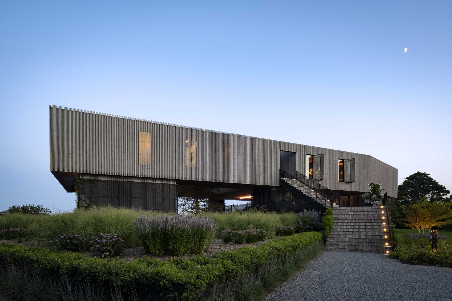 This elevated two-story house with ocean views allows the yard and its plantings to slide underneath and reach through the stories above.