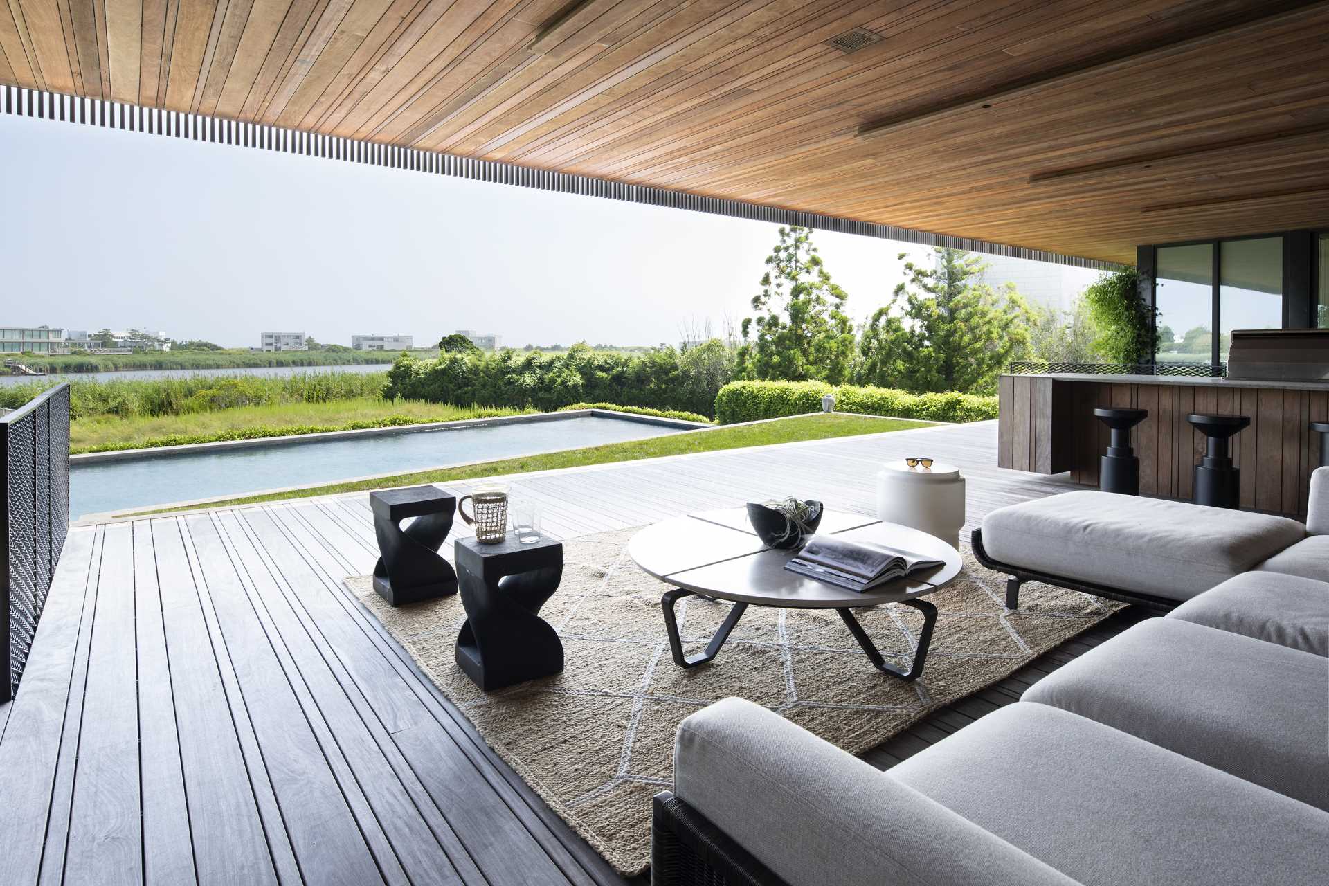 A covered outdoor living room overlooks the swimming pool, with steps connecting the various levels.