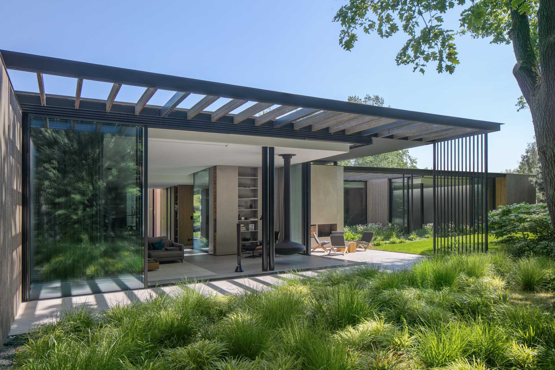 Retracting glass walls connect the interior spaces with the outdoors, while the floors extend beyond the building outline to merge the spaces.