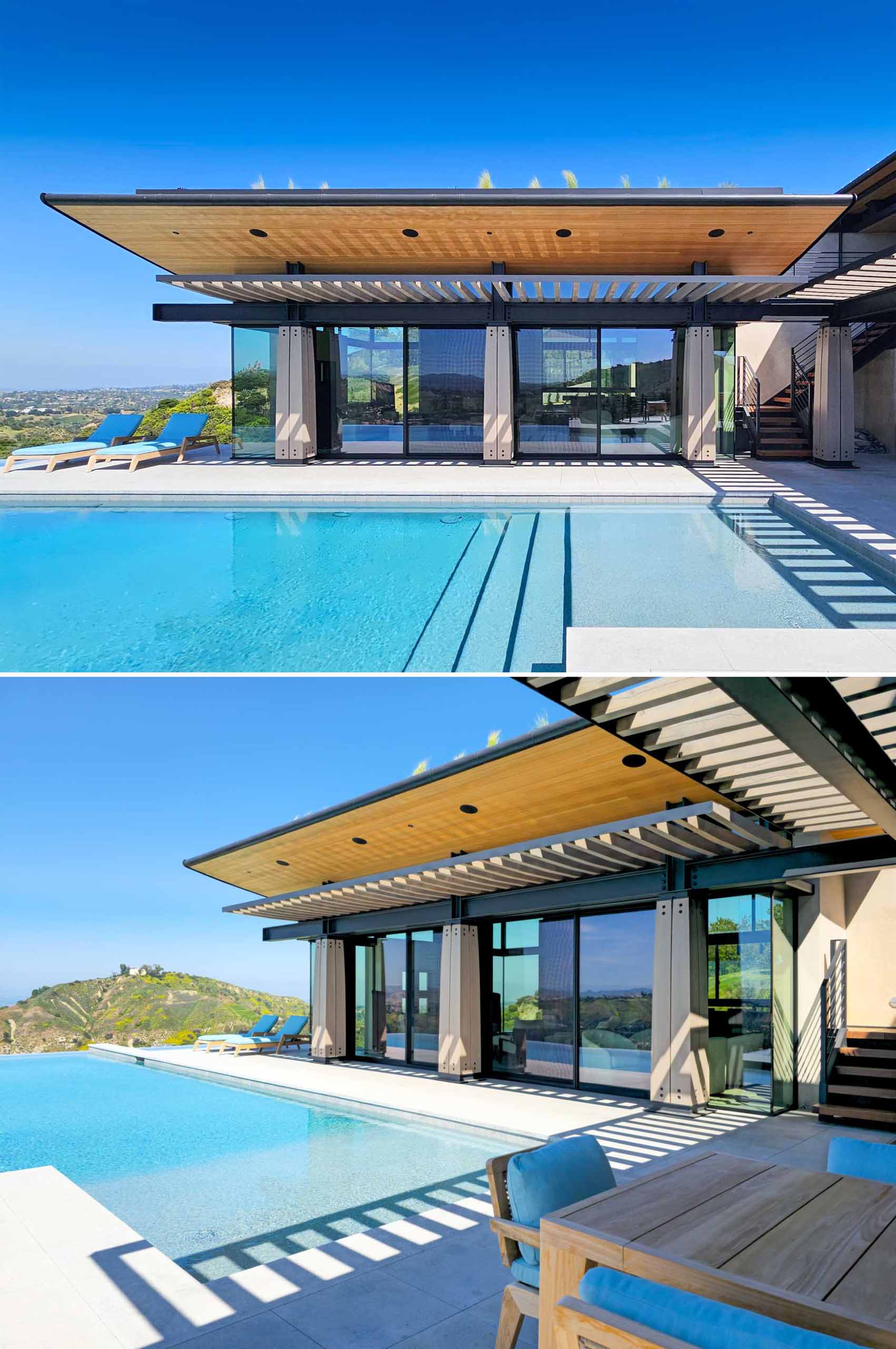 Wood and steel columns are on display by the pool of this contemporary house, while the overhanging roof provides shelter and shade, and a pergola defines an outdoor living space furnished with a couch, dining area, and bbq.