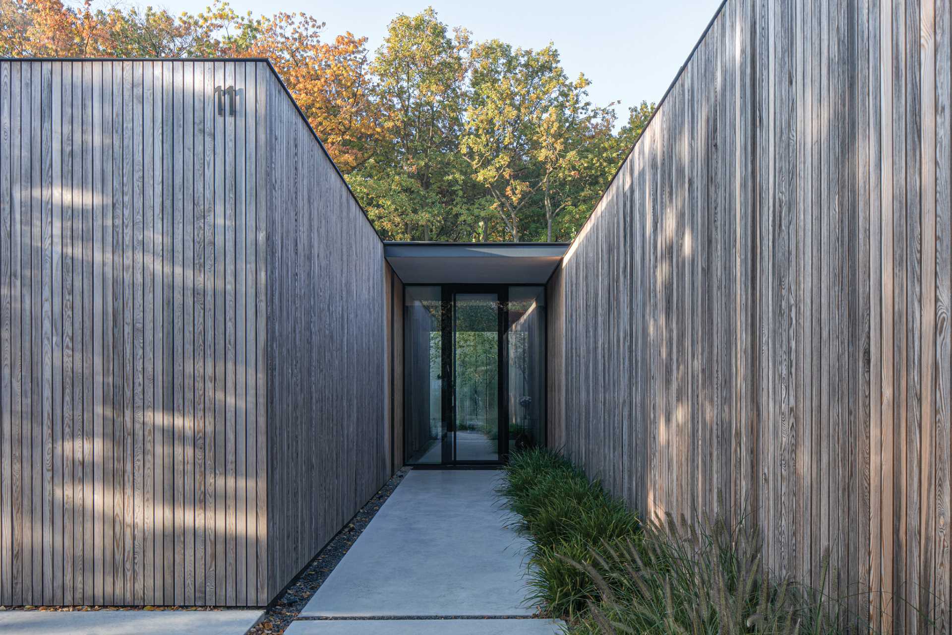 This modern house with its vertical wood facade, blends discreetly into the surrounding dense forest.