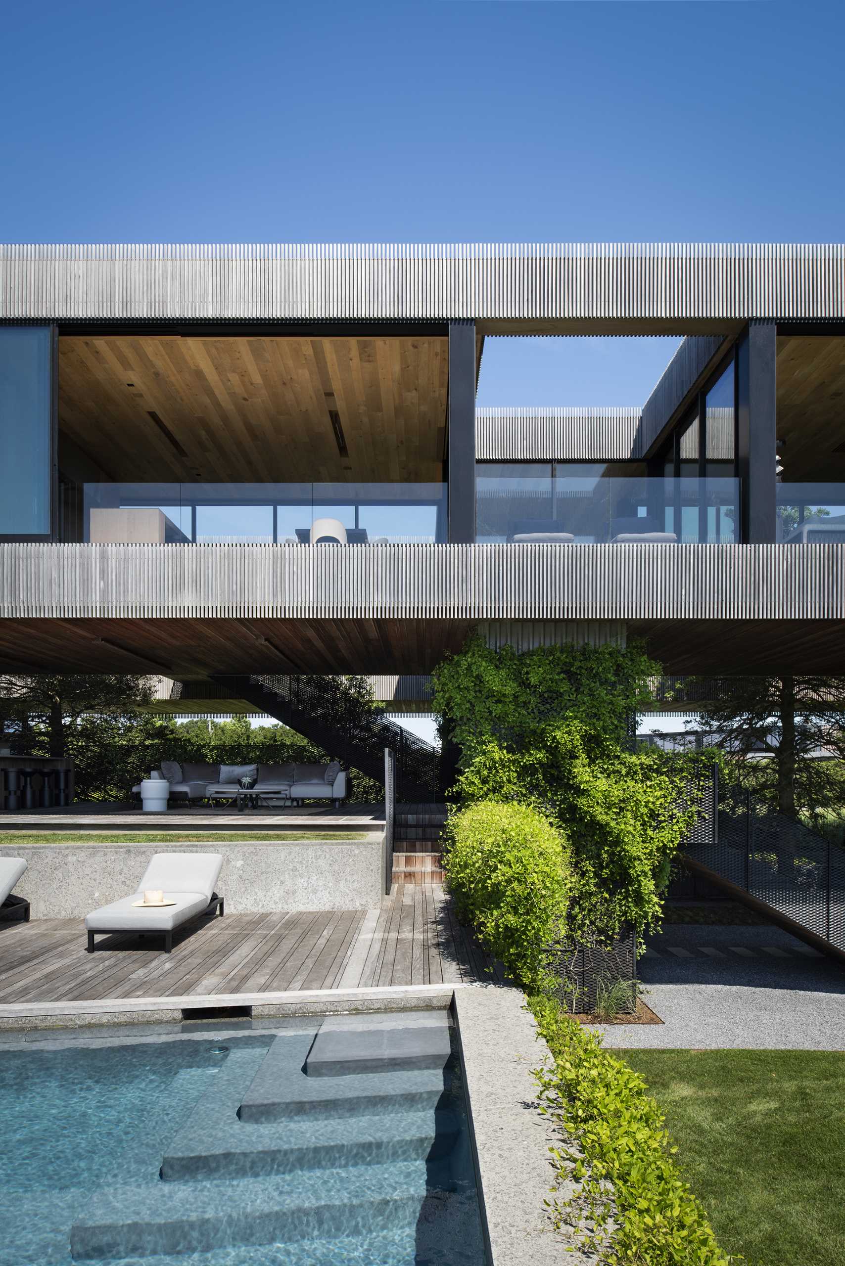 A modern home with elevated living spaces also includes a swimming pool and covered outdoor living room.
