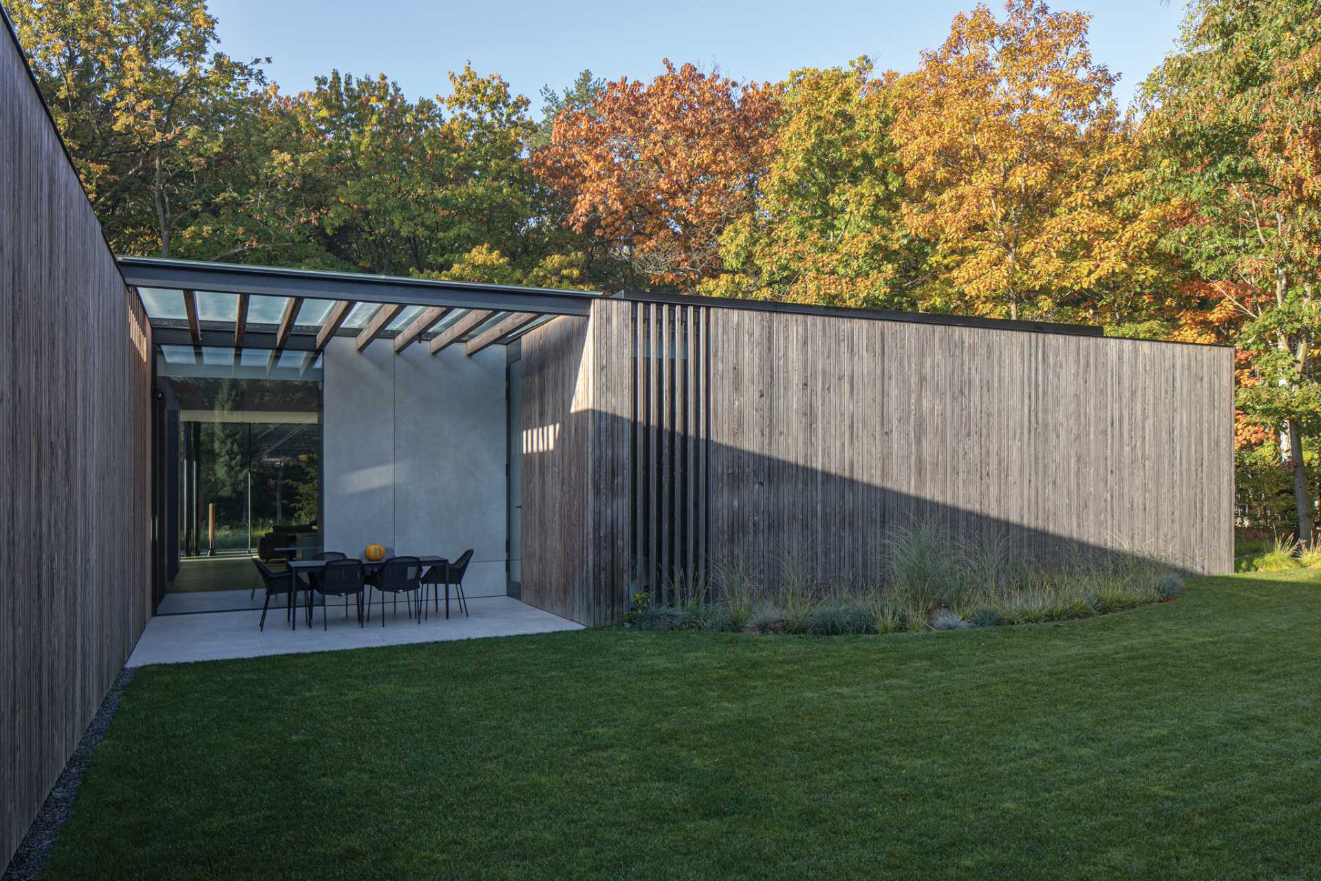 The wood siding wraps around from the facade to the side and rear of the home, with some sections missing the wood to allow the natural light to pass through to the interior spaces.