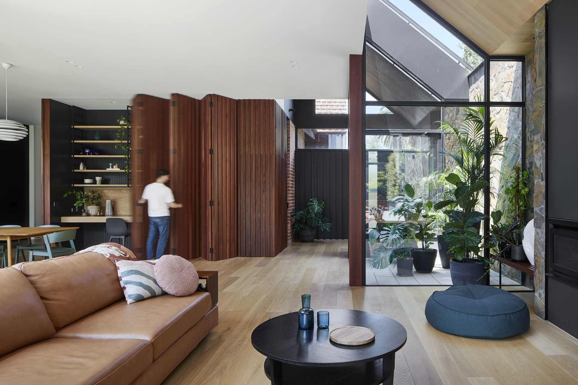 A modern home interior includes a wood accent wall in the dining room that opens to reveal a hidden office for two.