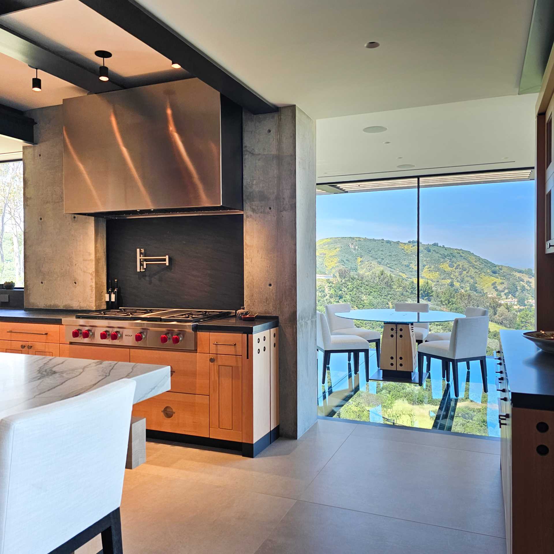 A modern cantilevered dining room off the kitchen that has glass walls and floor.