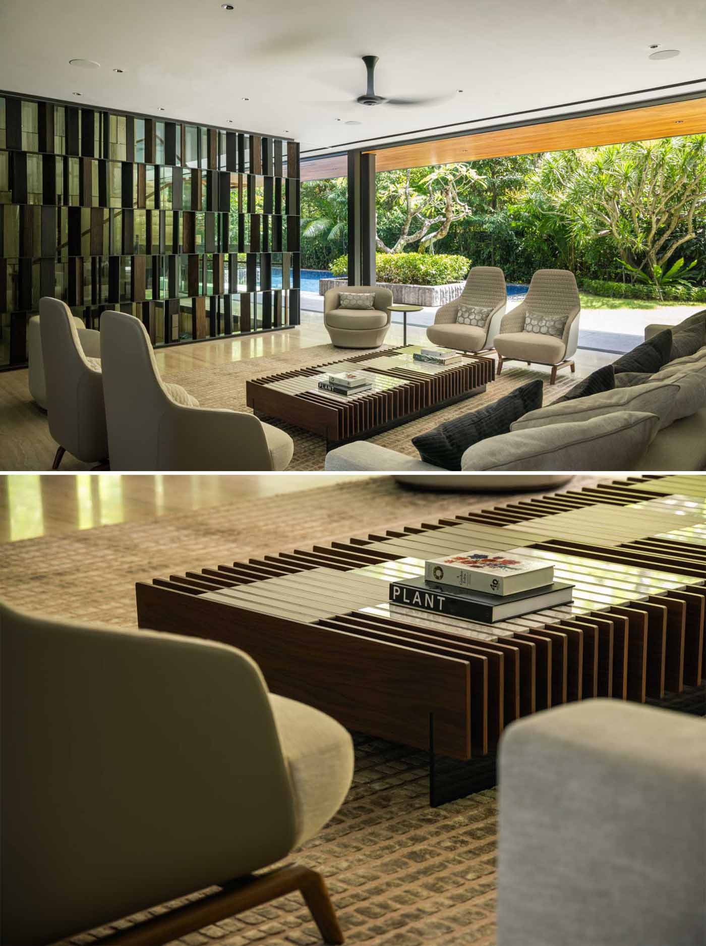 A modern living room has gl، walls that open to the outdoors.