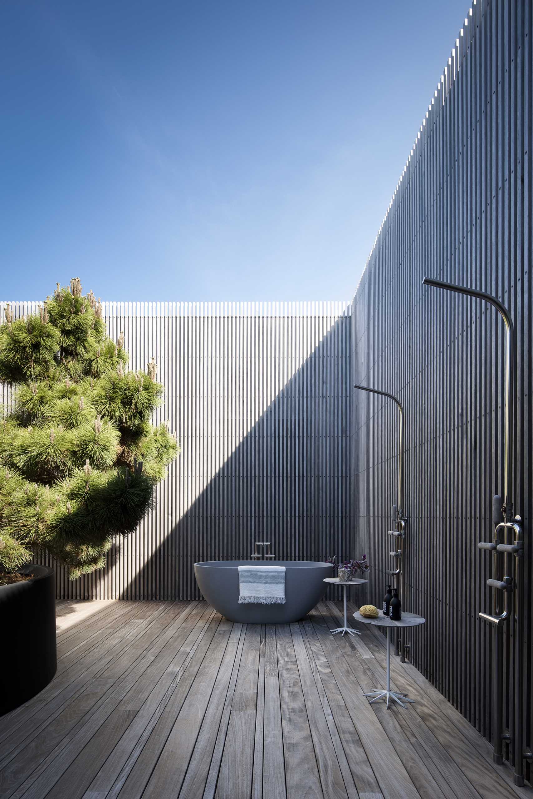 A modern home with an outdoor shower for two as well as a freestanding bathtub.