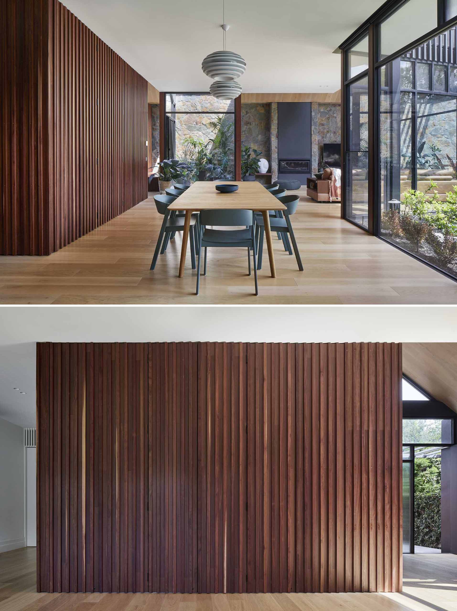A modern home interior includes a wood accent wall in the dining room that opens to reveal a hidden office for two.