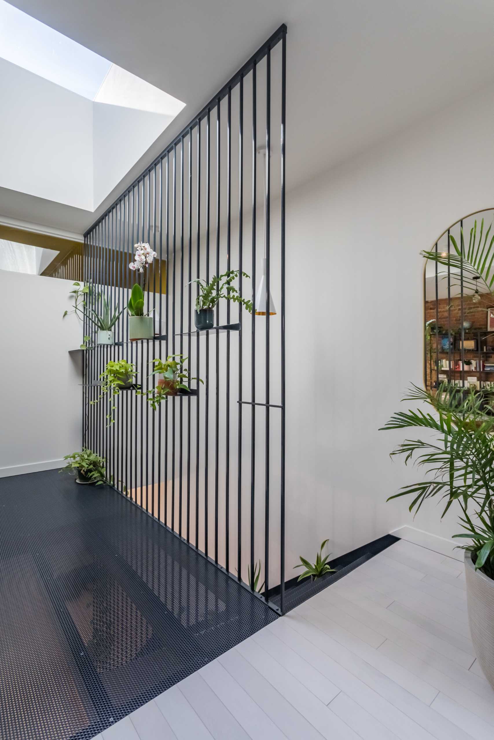 The metal screen from the lower level continues through to the upper level and includes shelves for plants.