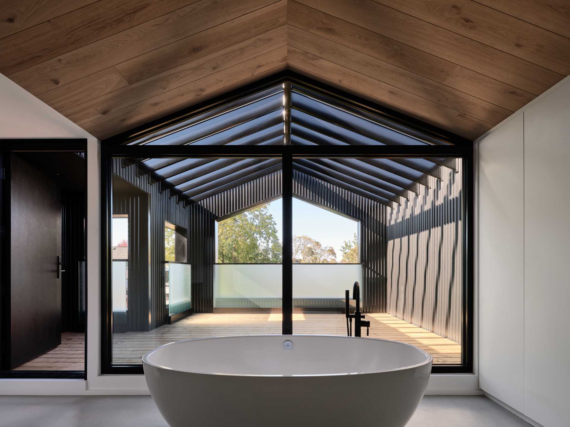 A modern bathroom with a freestanding bathtub opens to a private deck.