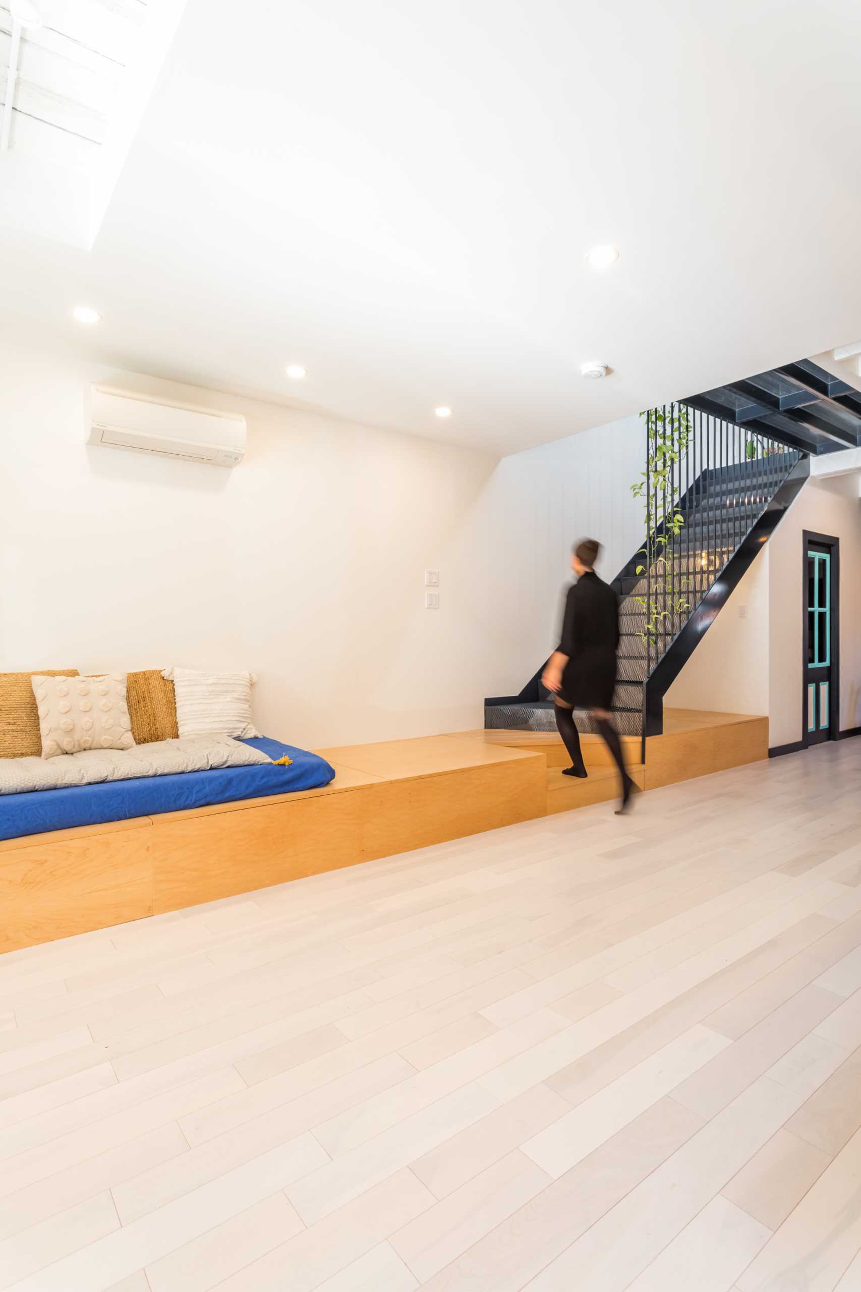 Opposite the kitchen is a wood platform that's home to a couch and leads to the steel stairs. A powder room with patterned tiles has been tucked away underneath the stairs.