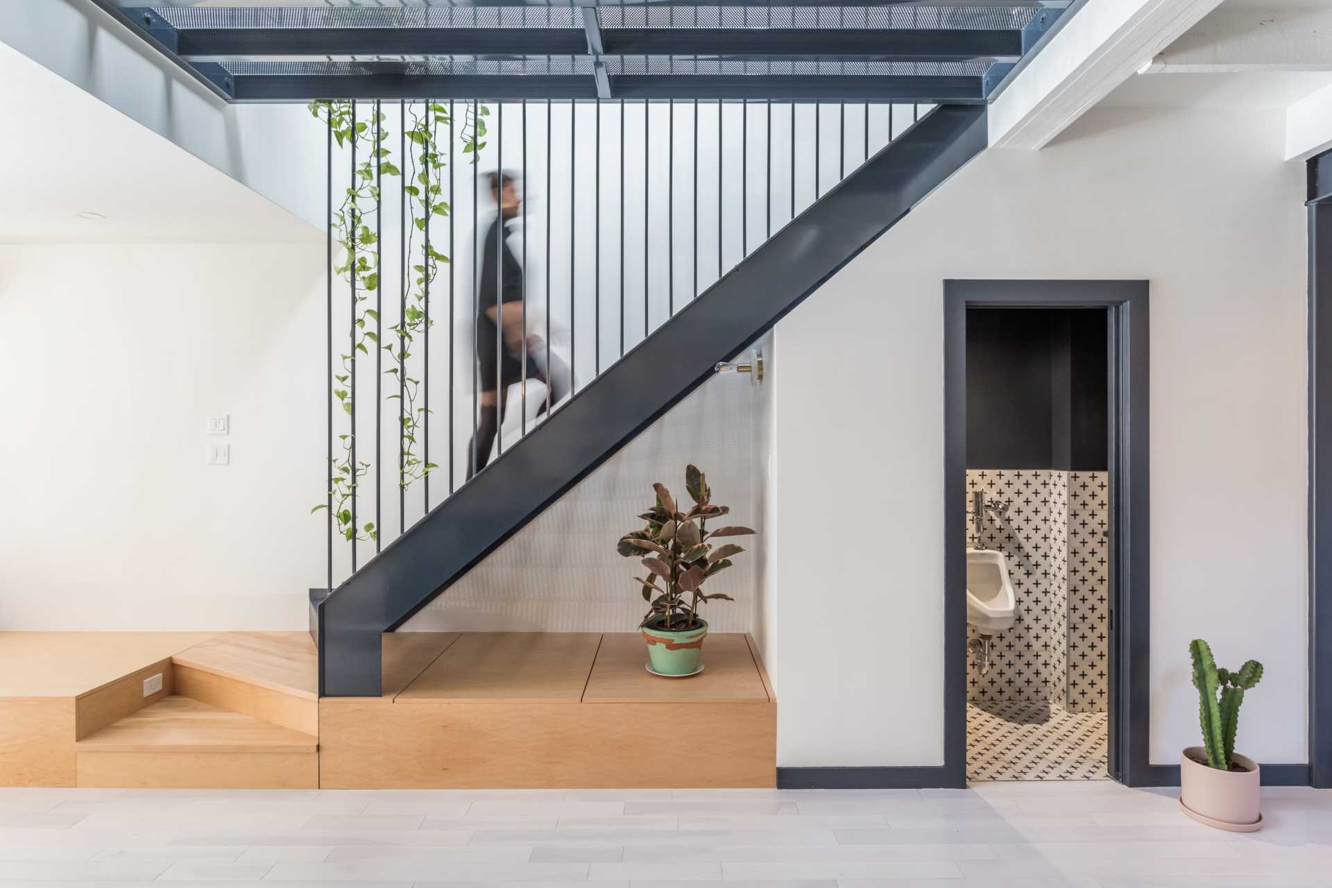 Opposite the kitchen is a wood platform that's home to a couch and leads to the steel stairs. A powder room with patterned tiles has been tucked away underneath the stairs.