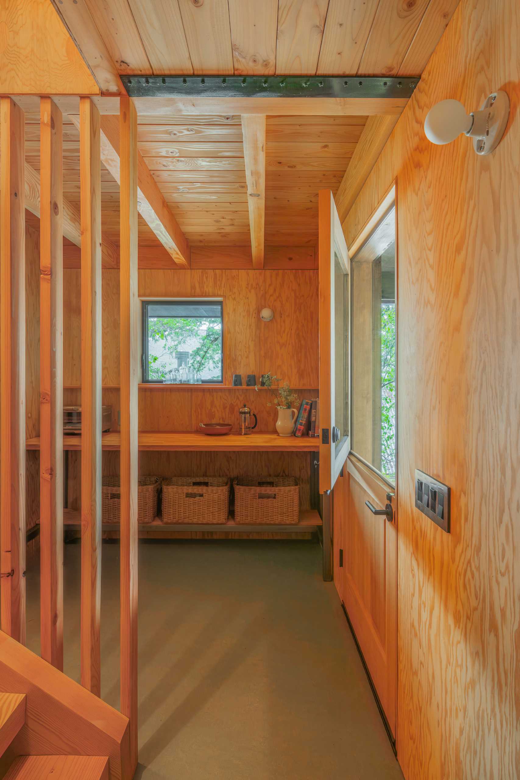 A Dutch door creates a casual entrance to the cabin. Inside the wood-lined cabin, there's a wall with storage, while the floor is finished in a sage green.