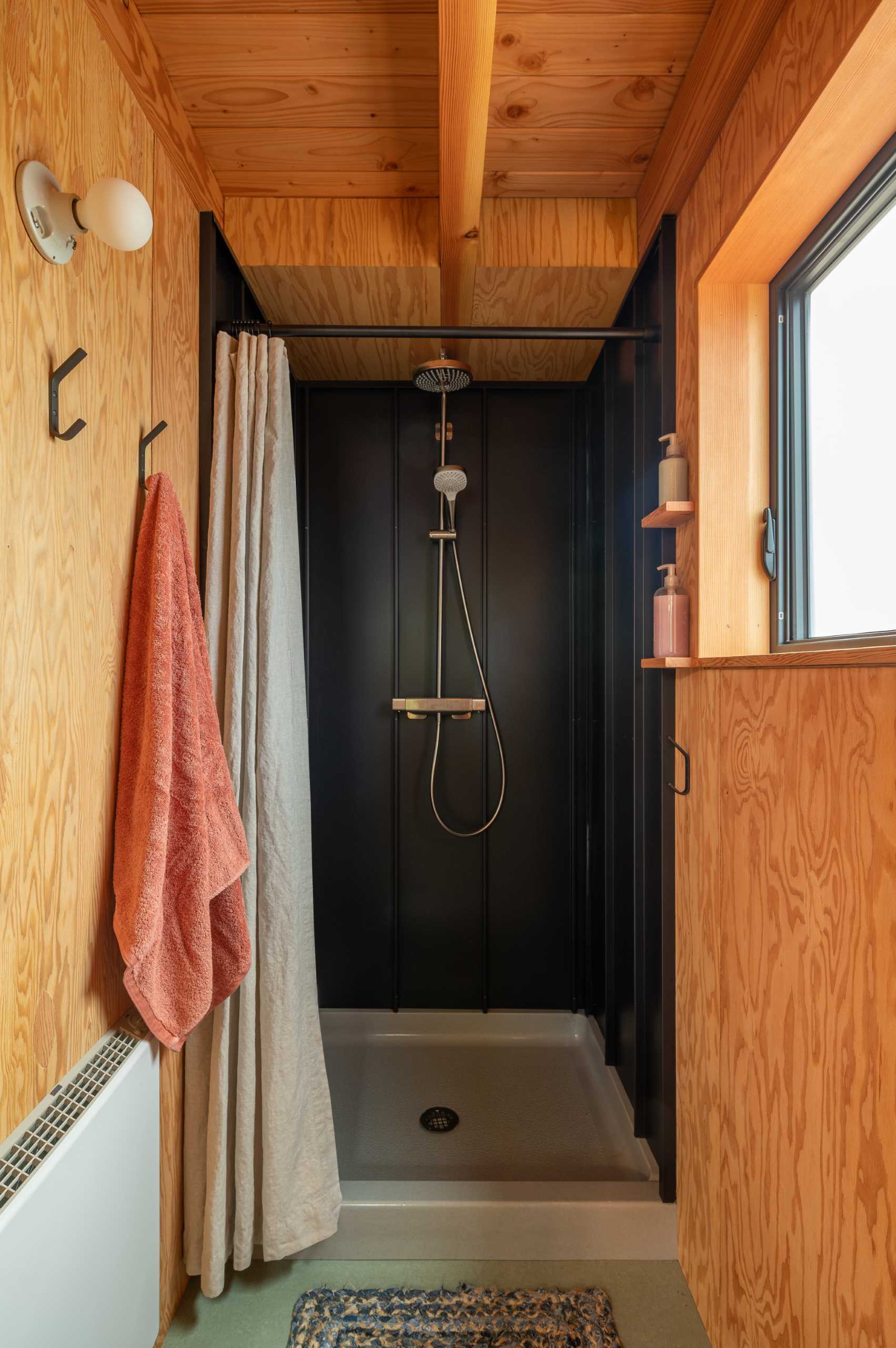 The shower in this cabin has been lined with low gloss black standing seam metal roofing.
