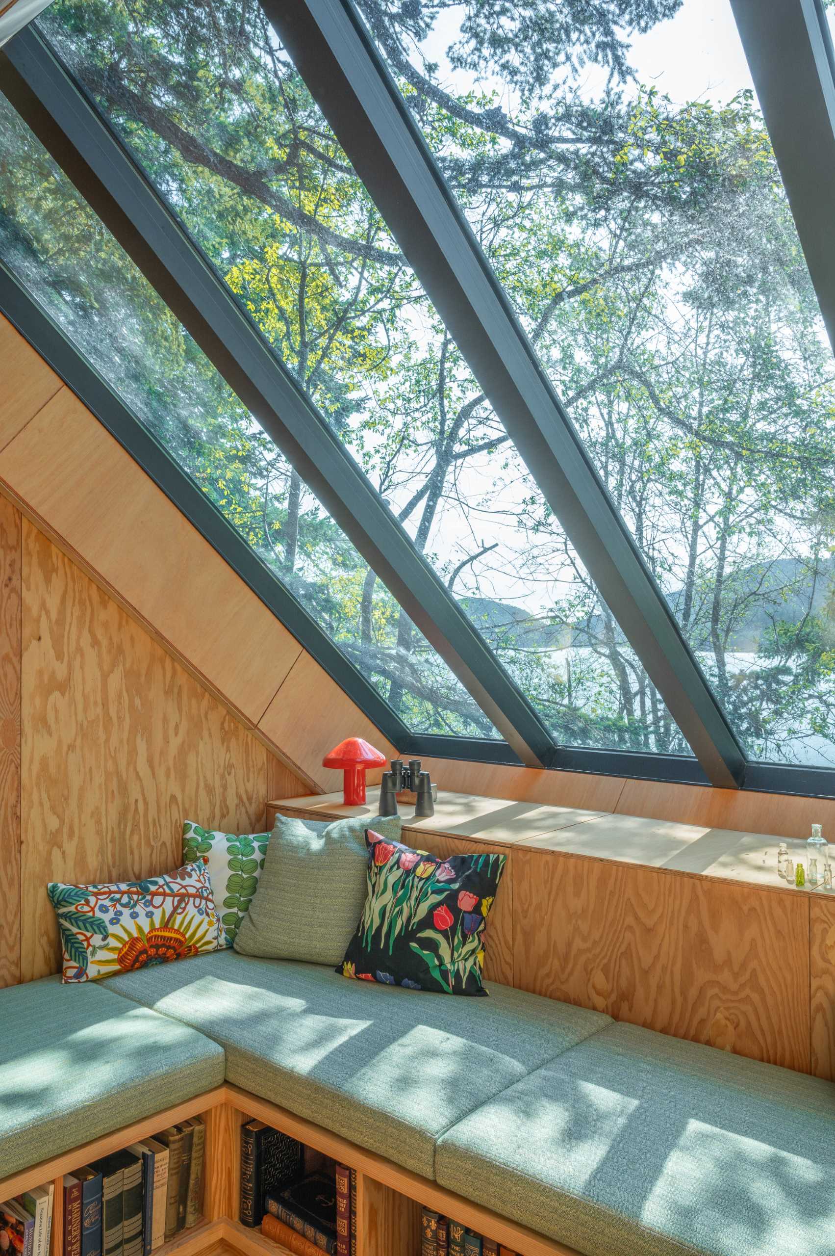 At the top of the stairs in this cabin, there's an open lounge area beneath custom skylights. Custom furniture with open storage underneath is topped with upholstered cushions, creating a cozy lounge.