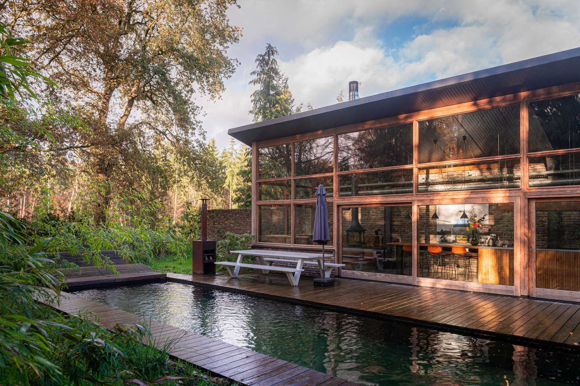 A modern home with rough and rugged materials like bricks and wood, also has a natural swimming pool.