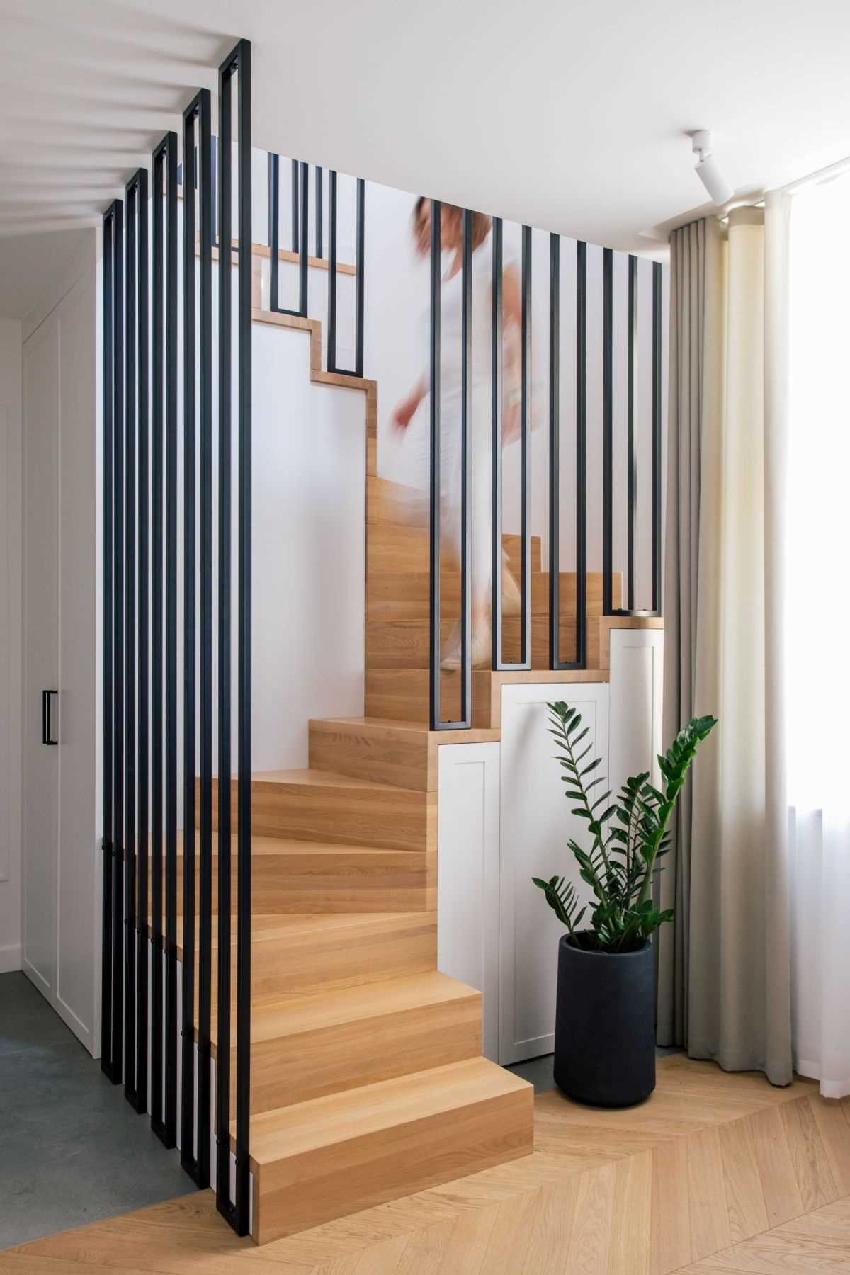 Wood stairs with contrasting black metal accents lead to the upper floor of this modern apartment.