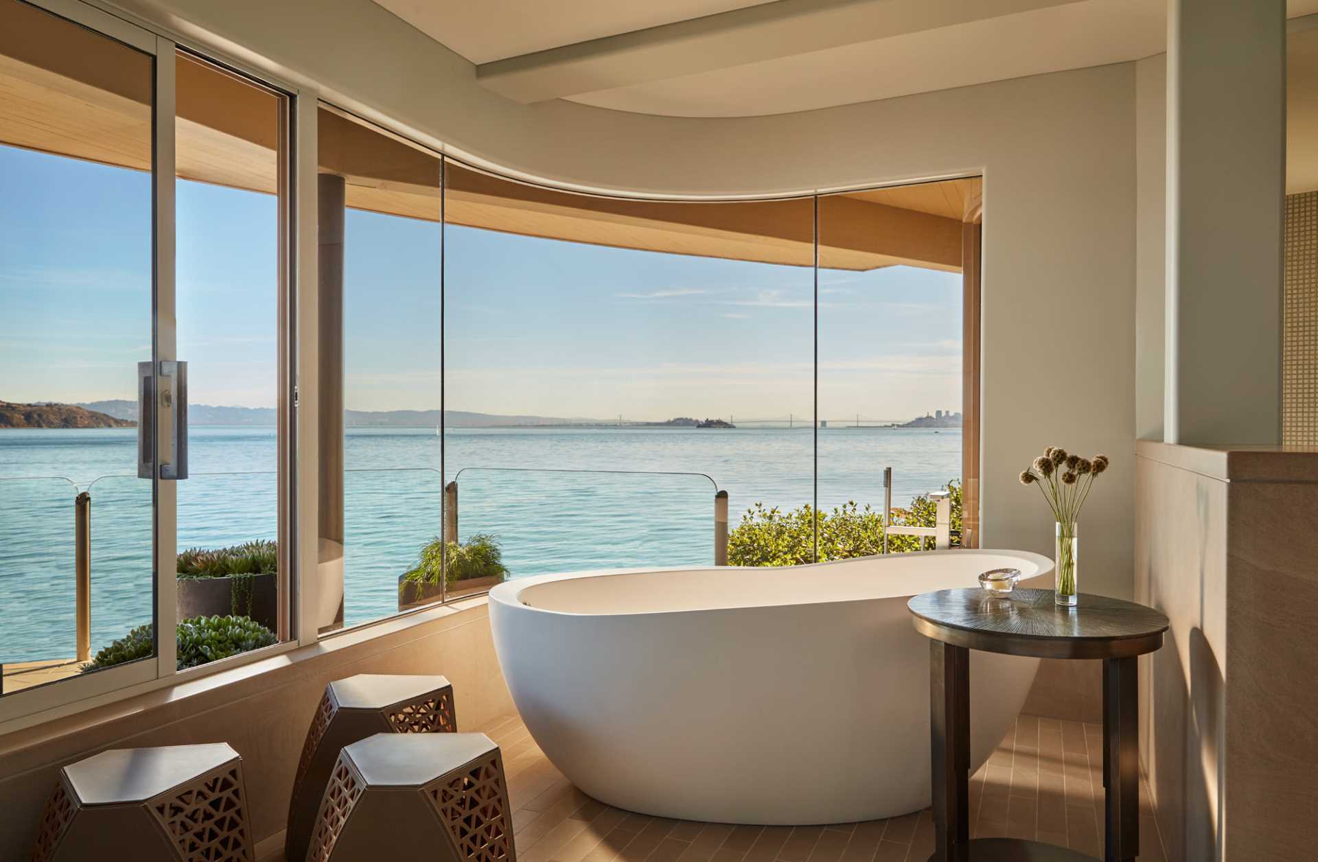 A modern bathroom with a freestanding bathtub positioned in front of curved windows.