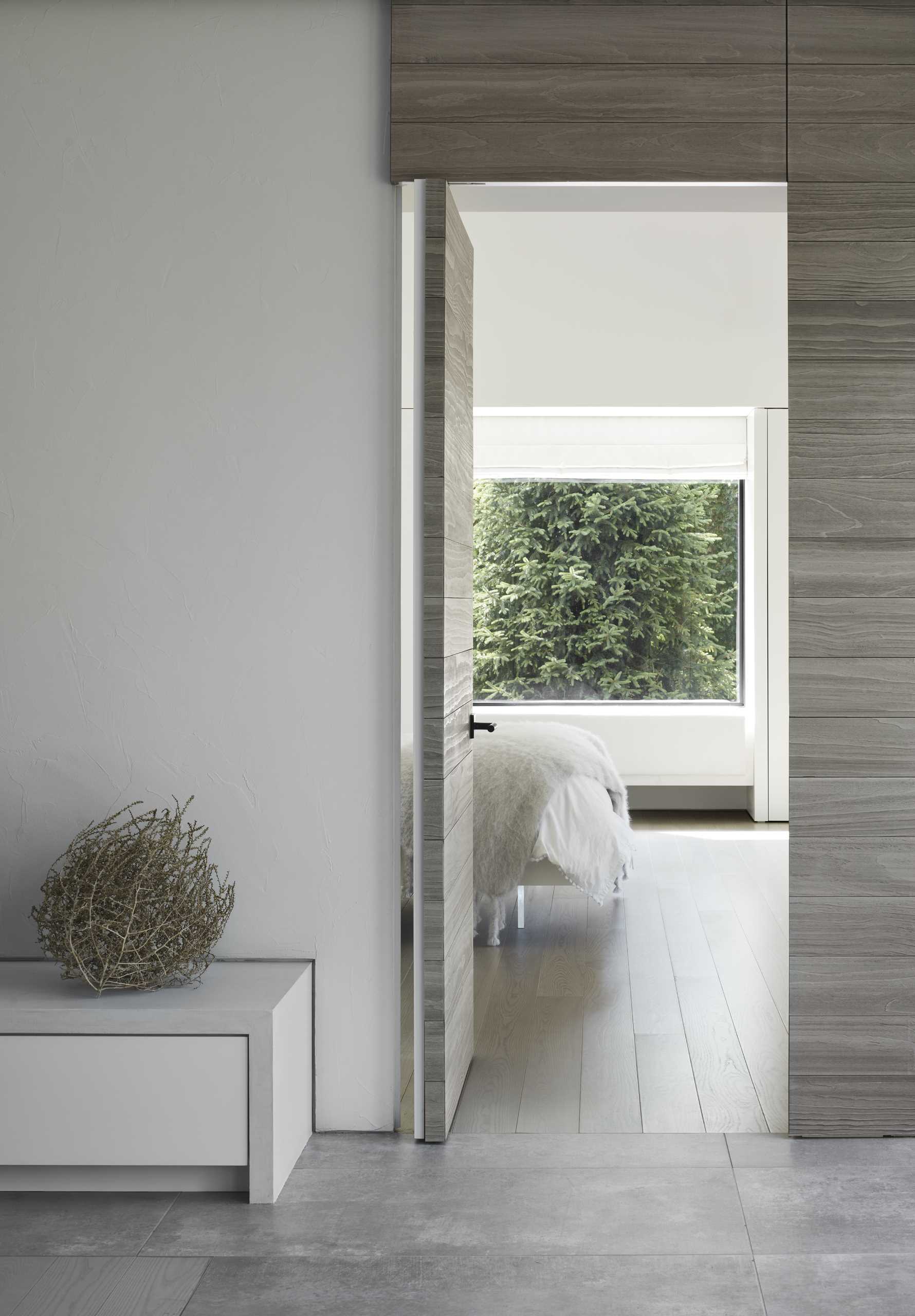 A door that blends into the wood wall, opens to reveal one of the bedrooms.
