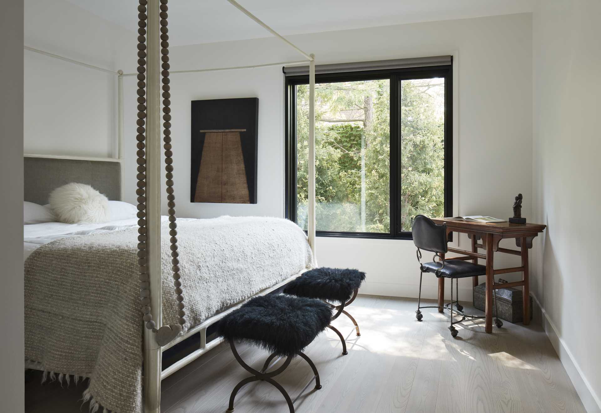 A contemporary bedroom a black window frame that complements the black furniture accents and art.