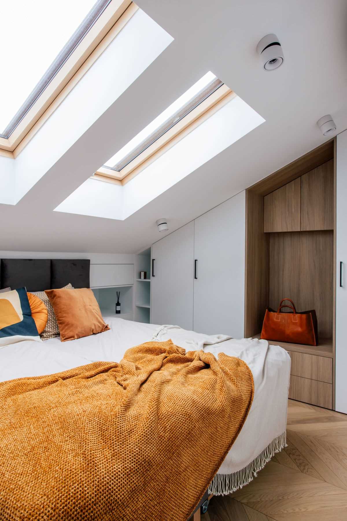 In this modern bedroom, there's multiple skylights, a built-in bench, and a wallpaper with a hot air balloon print.