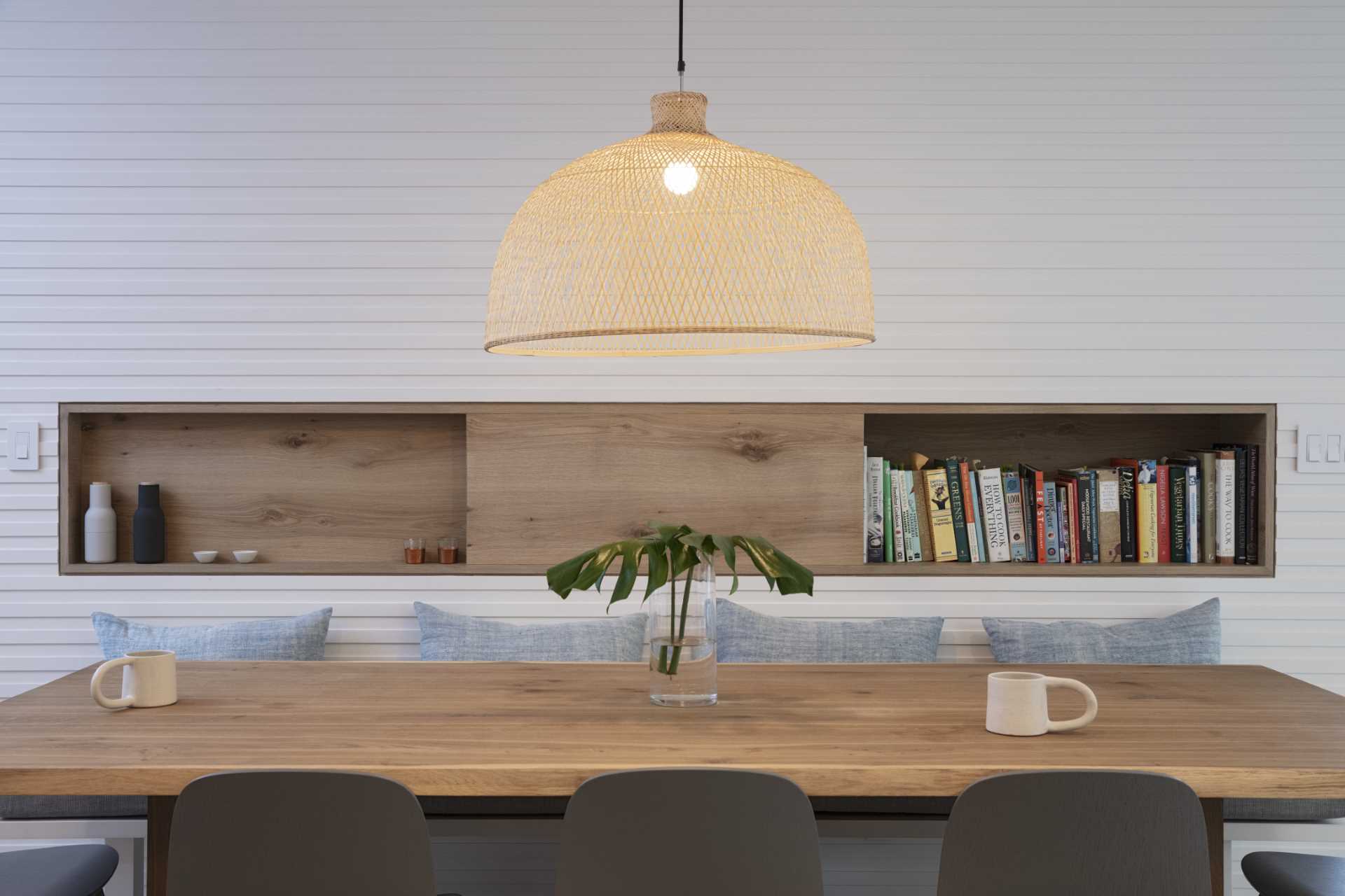 In this modern dining room, there's a built-in shelving niche and below it, there's bench seating.