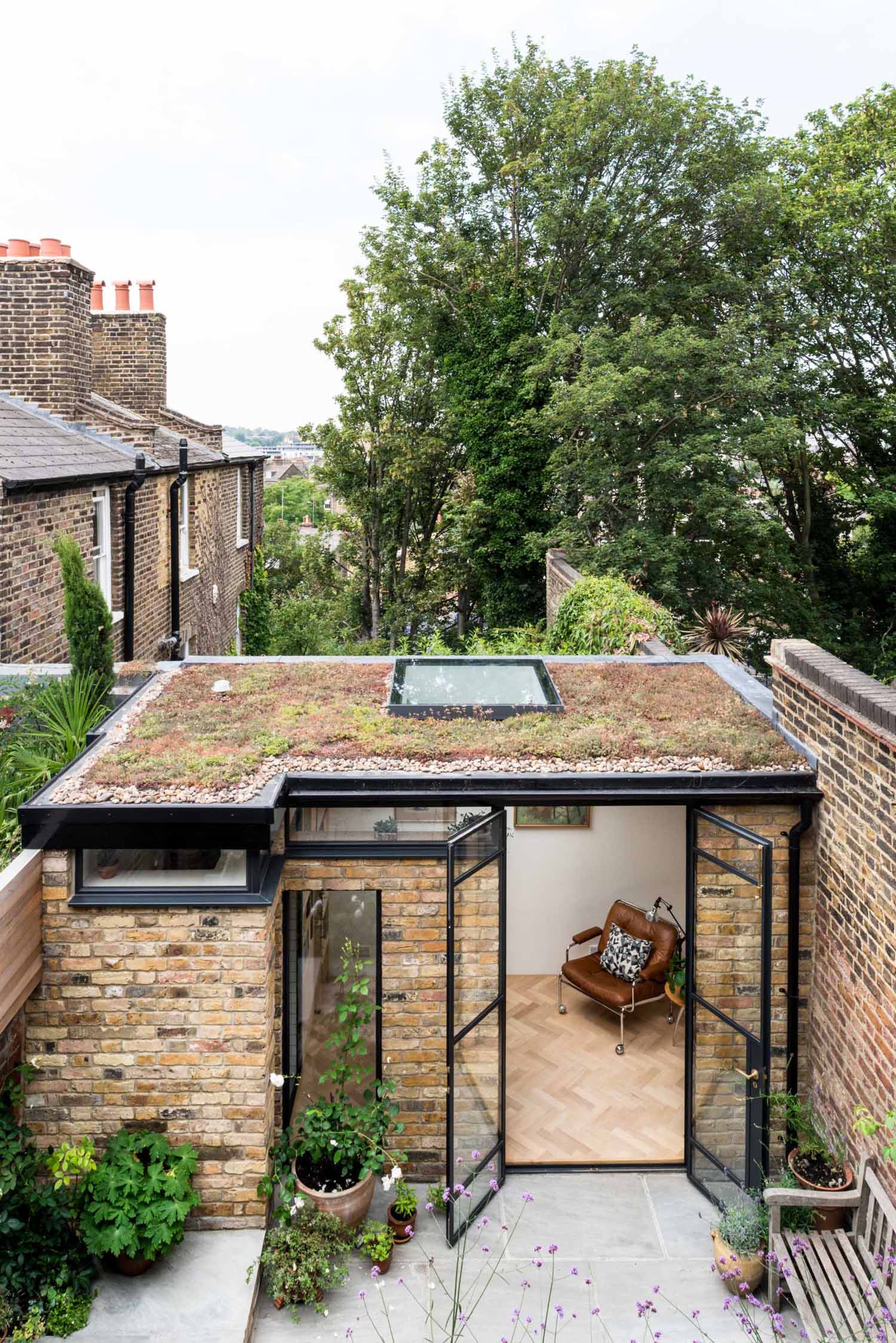 A new garden studio for a writer that includes a green roof, sitting area, built-in shelving, and a bathroom.