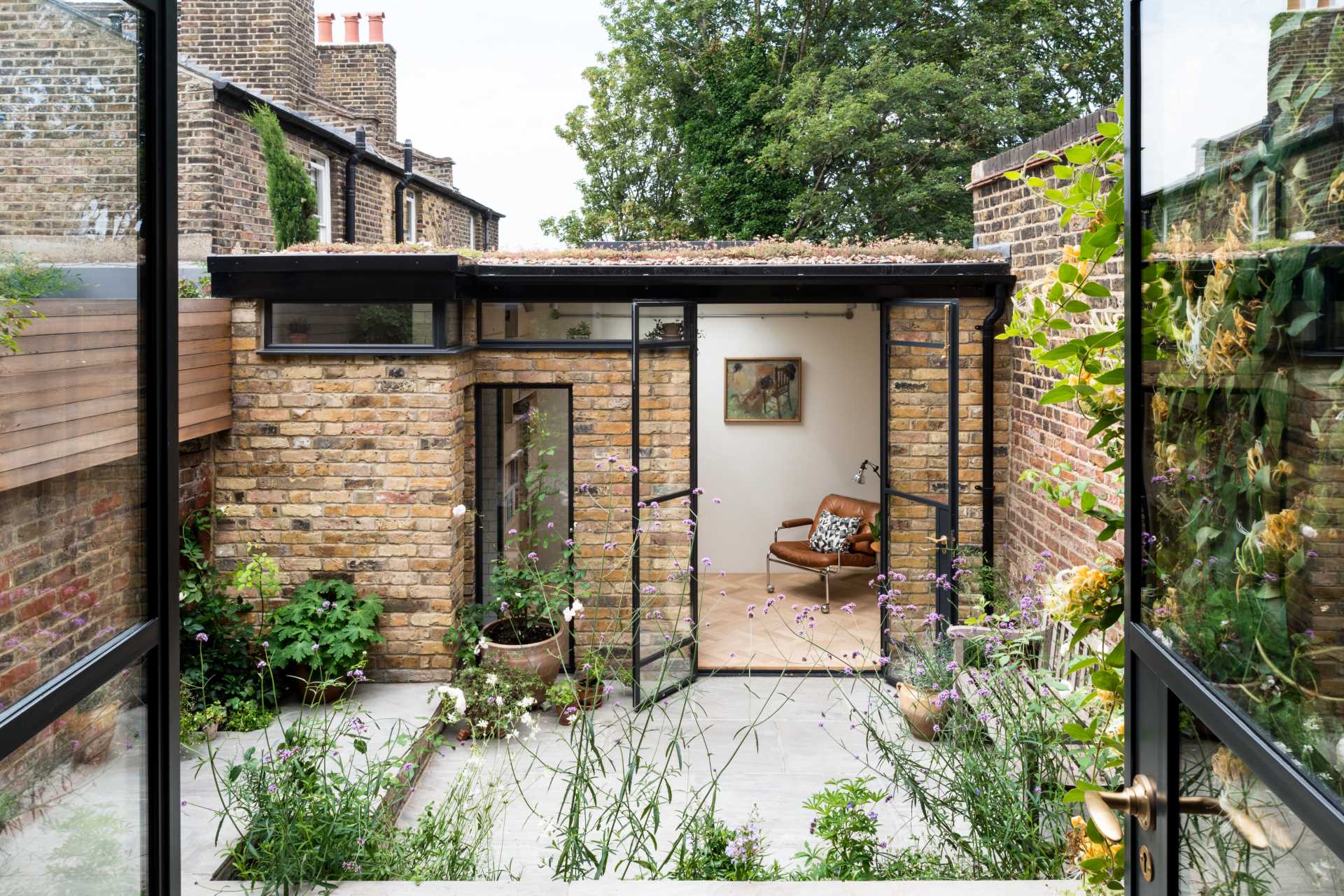 A new garden studio for a writer that includes a green roof, sitting area, built-in shelving, and a bathroom.