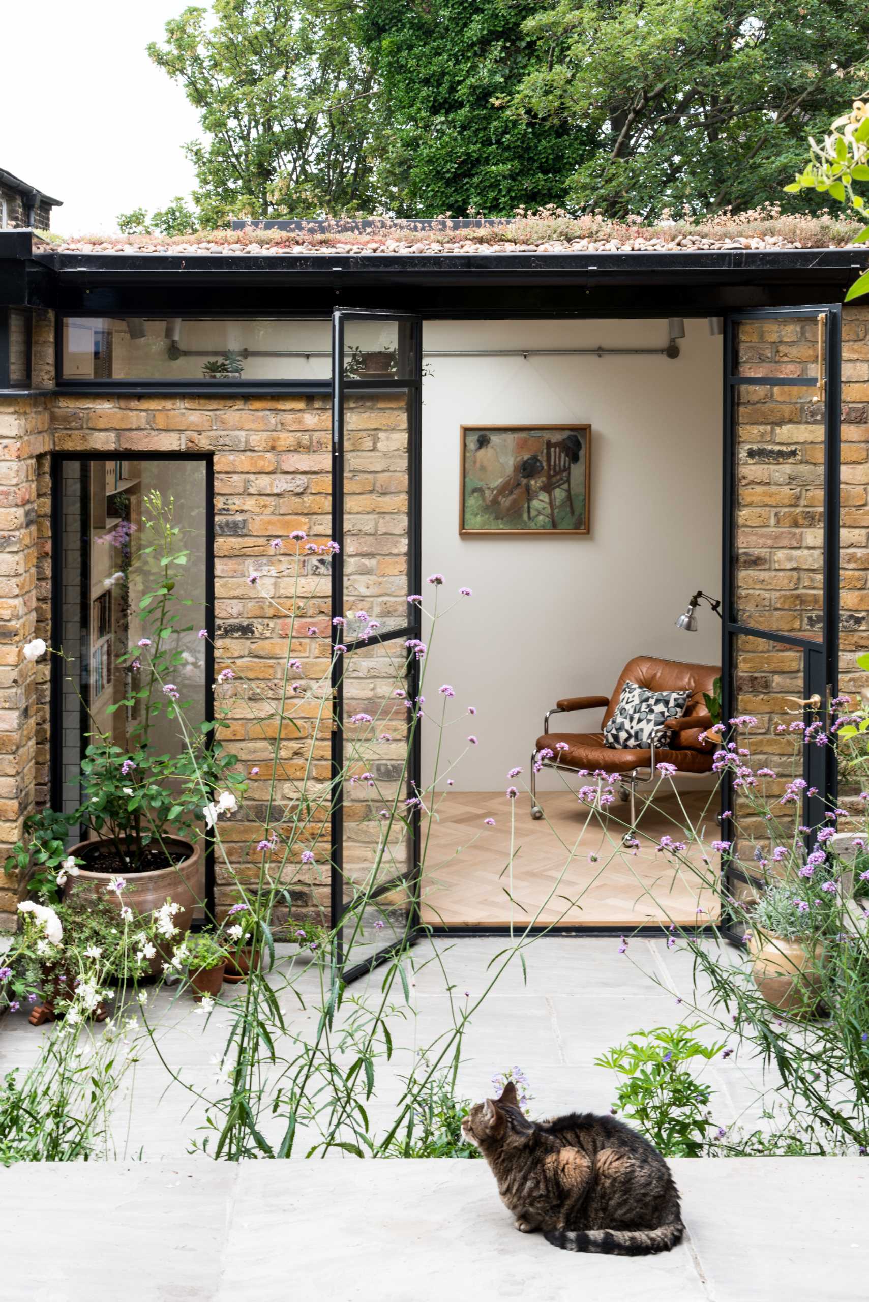 A new garden studio for a writer that includes a green roof, sitting area, built-in shelving, and a bathroom.