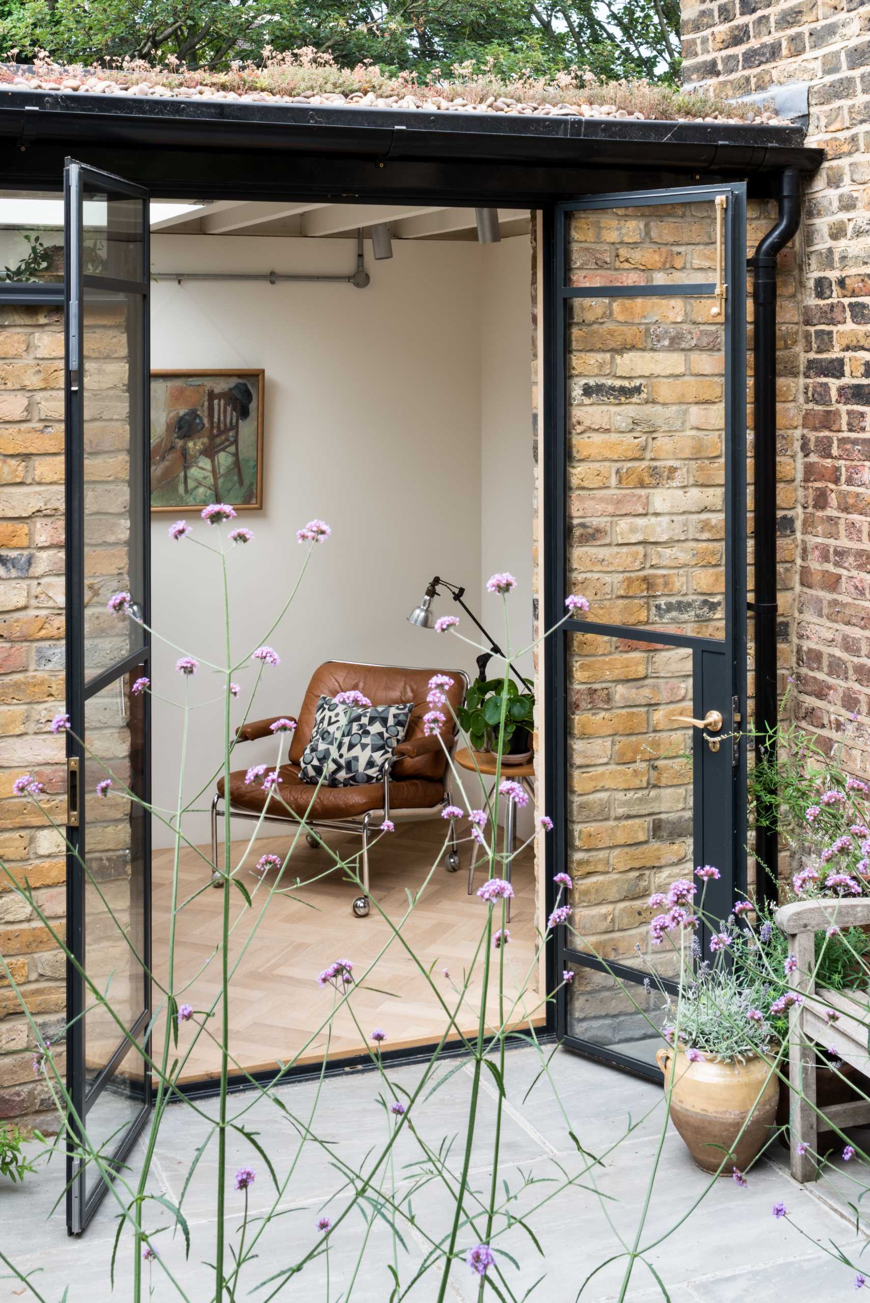 A new garden studio for a writer that includes a green roof, sitting area, built-in shelving, and a bathroom.