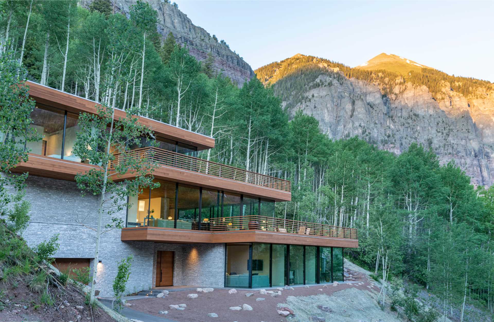 A modern home nestled into the steep cliffs appears as three cantilevered glass boxes.
