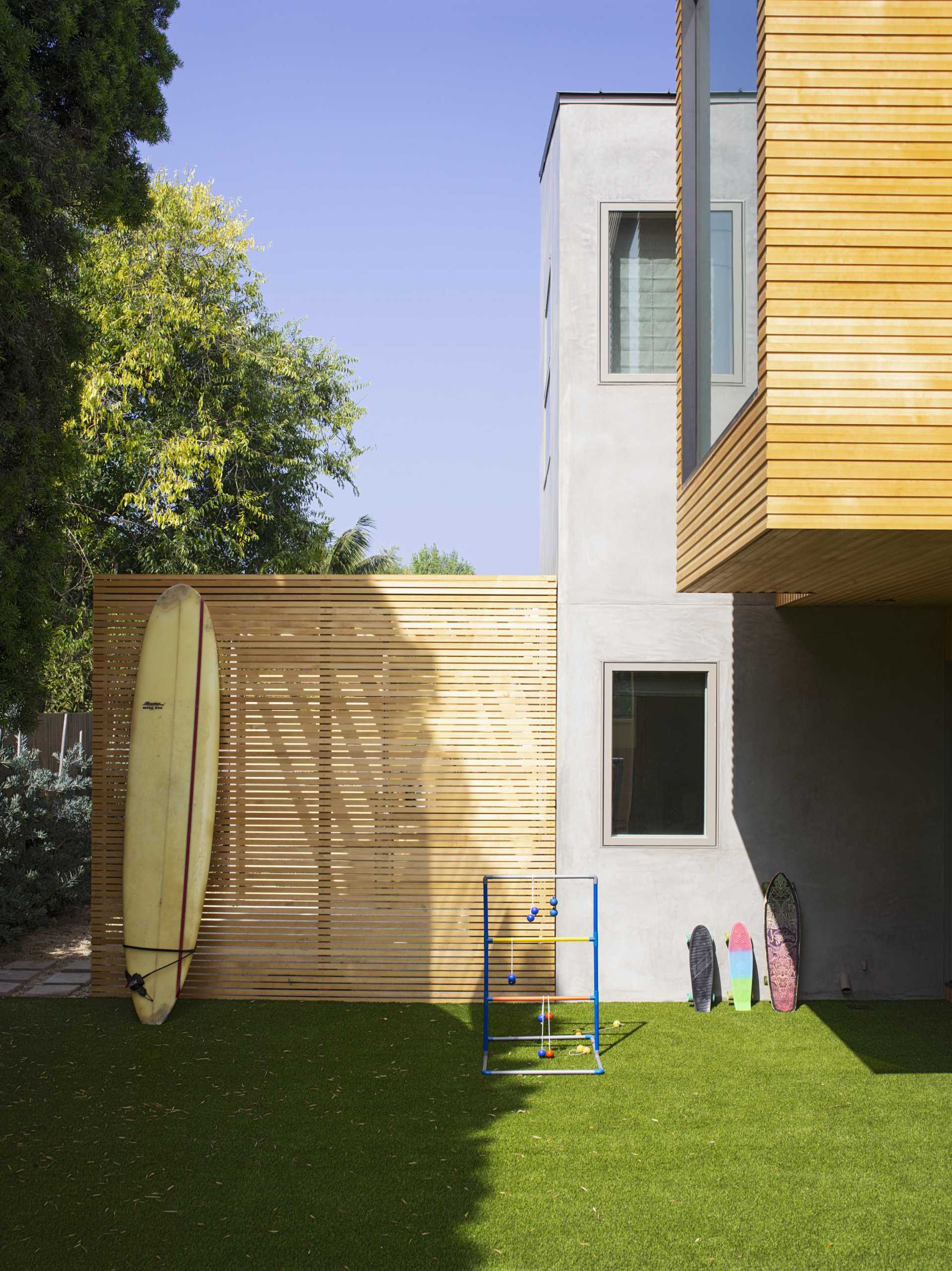 A modern house with an outdoor shower that's hidden from view with wood slats.