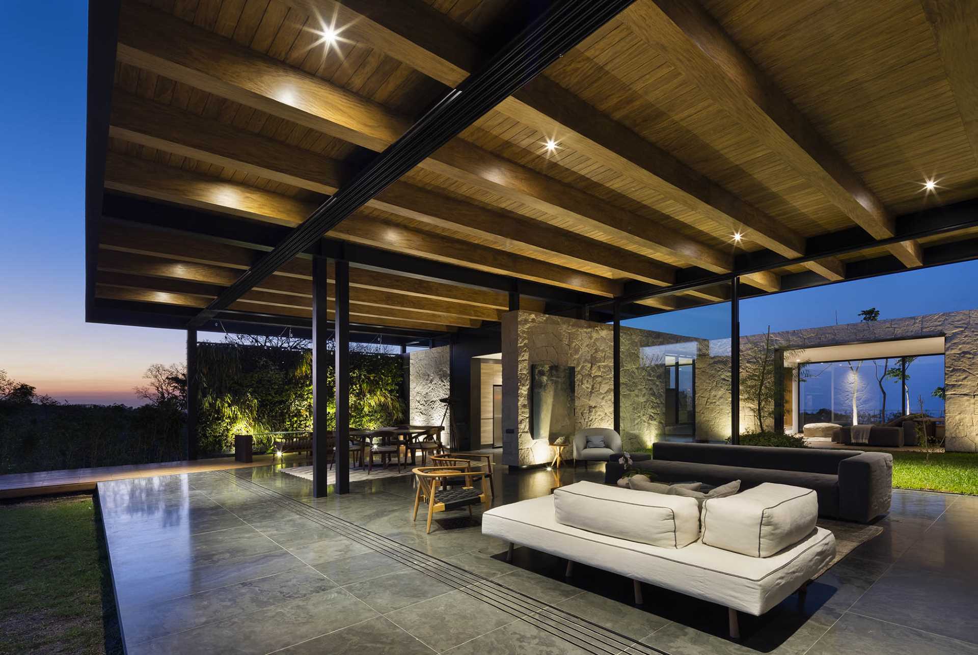A modern living room with exposed structural elements, that opens to the outdoors and swimming pool.